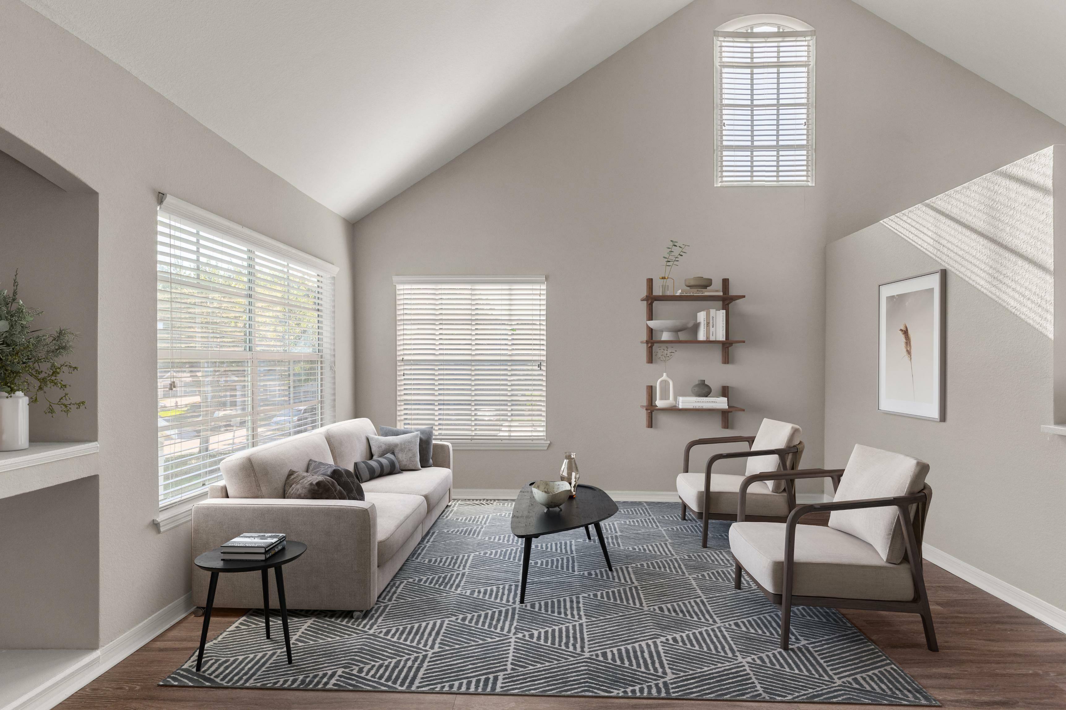 Elegant and modern living room with high ceilings, ample natural light, and stylish decor featuring a cozy sofa and chic armchairs on a geometric rug.