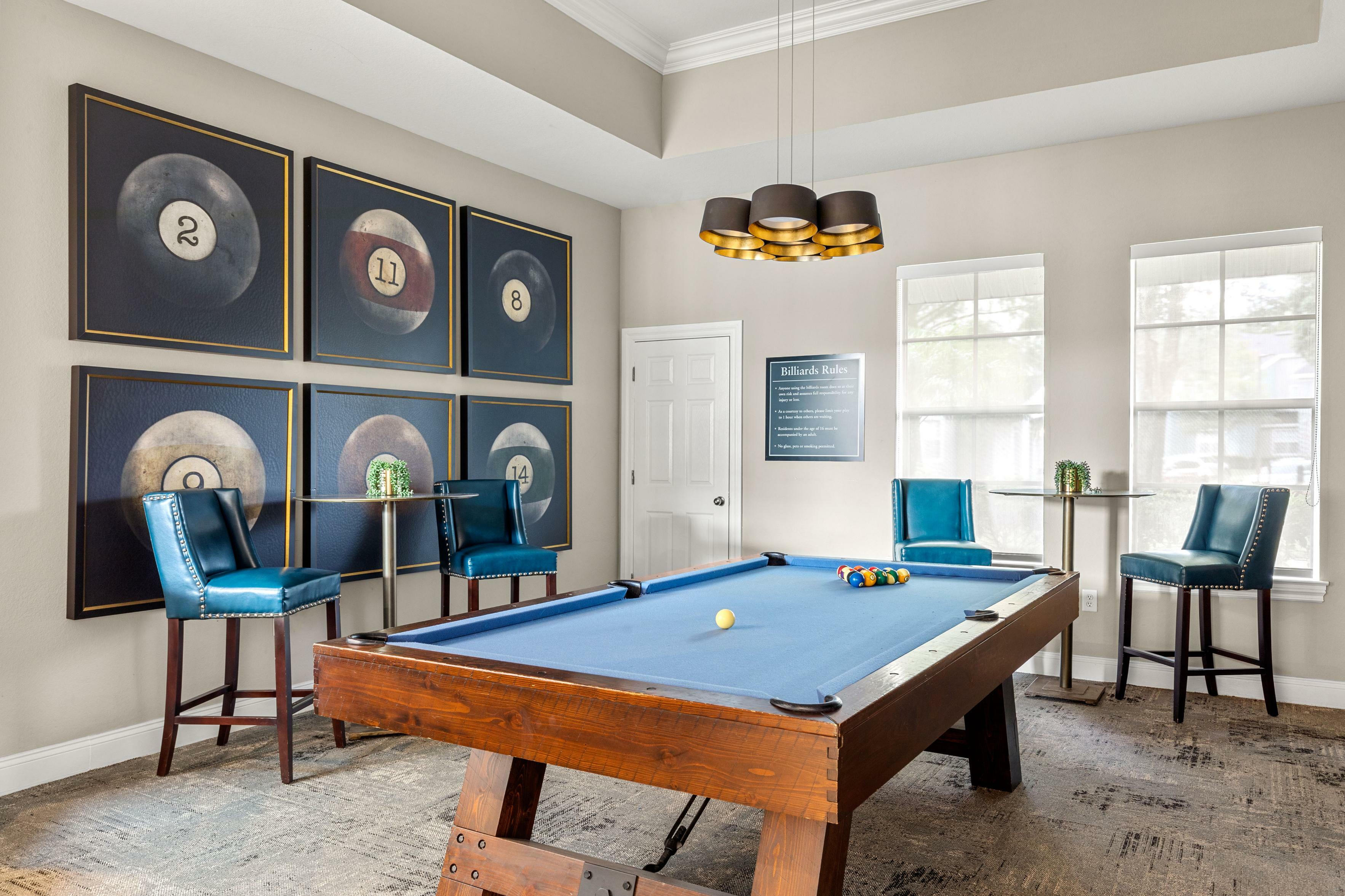 Chic game room with a stylish billiards table, vibrant blue chairs, and modern wall art, perfect for entertainment.