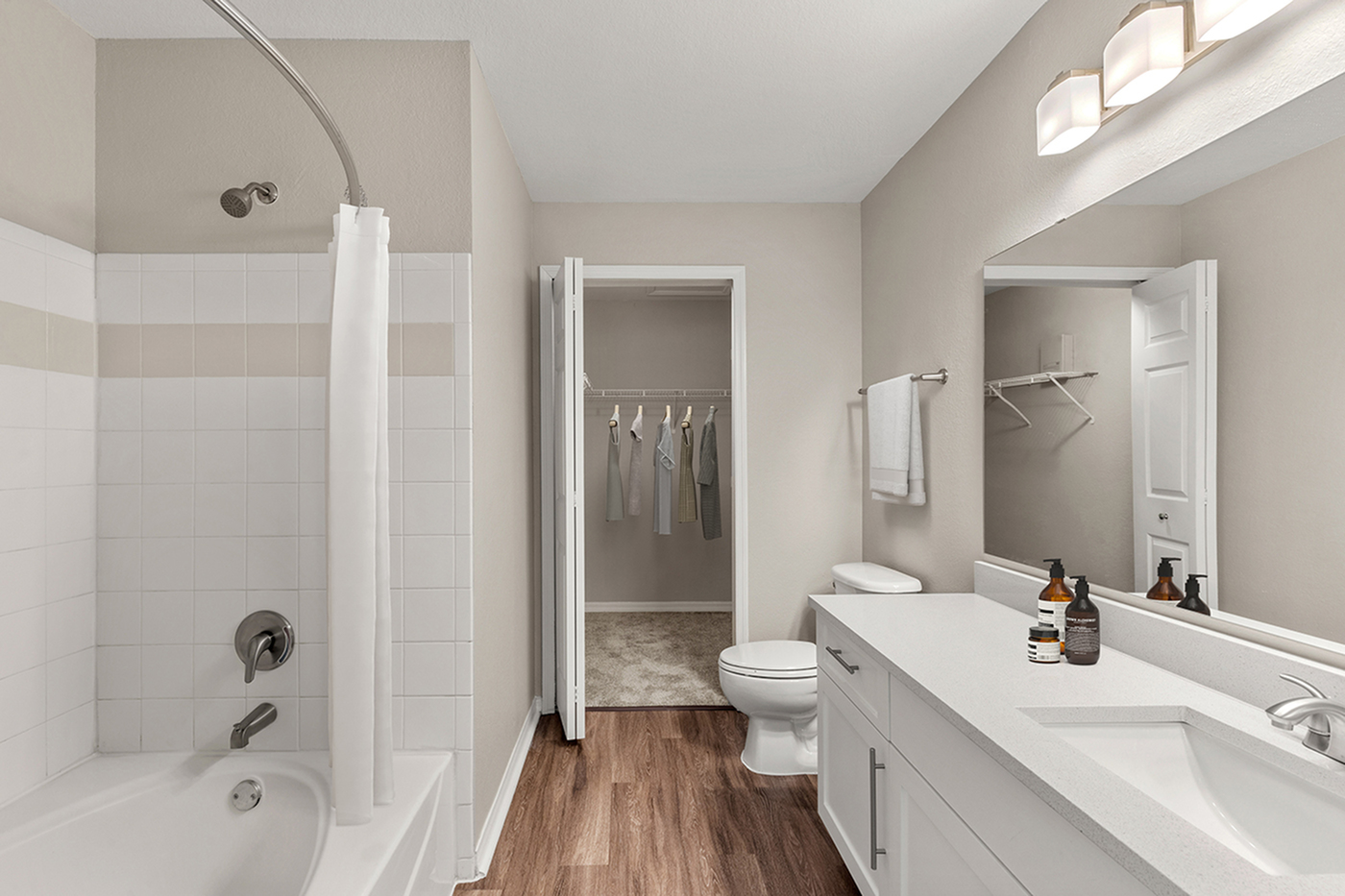 Elegant modern bathroom featuring a sleek white vanity, stylish lighting, and a cozy walk-in closet.