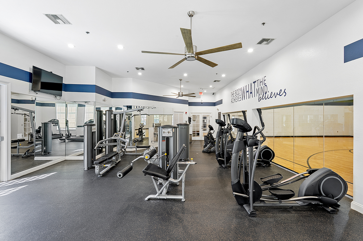 Modern fitness center with state-of-the-art exercise machines, mirrored walls, and motivational decor.