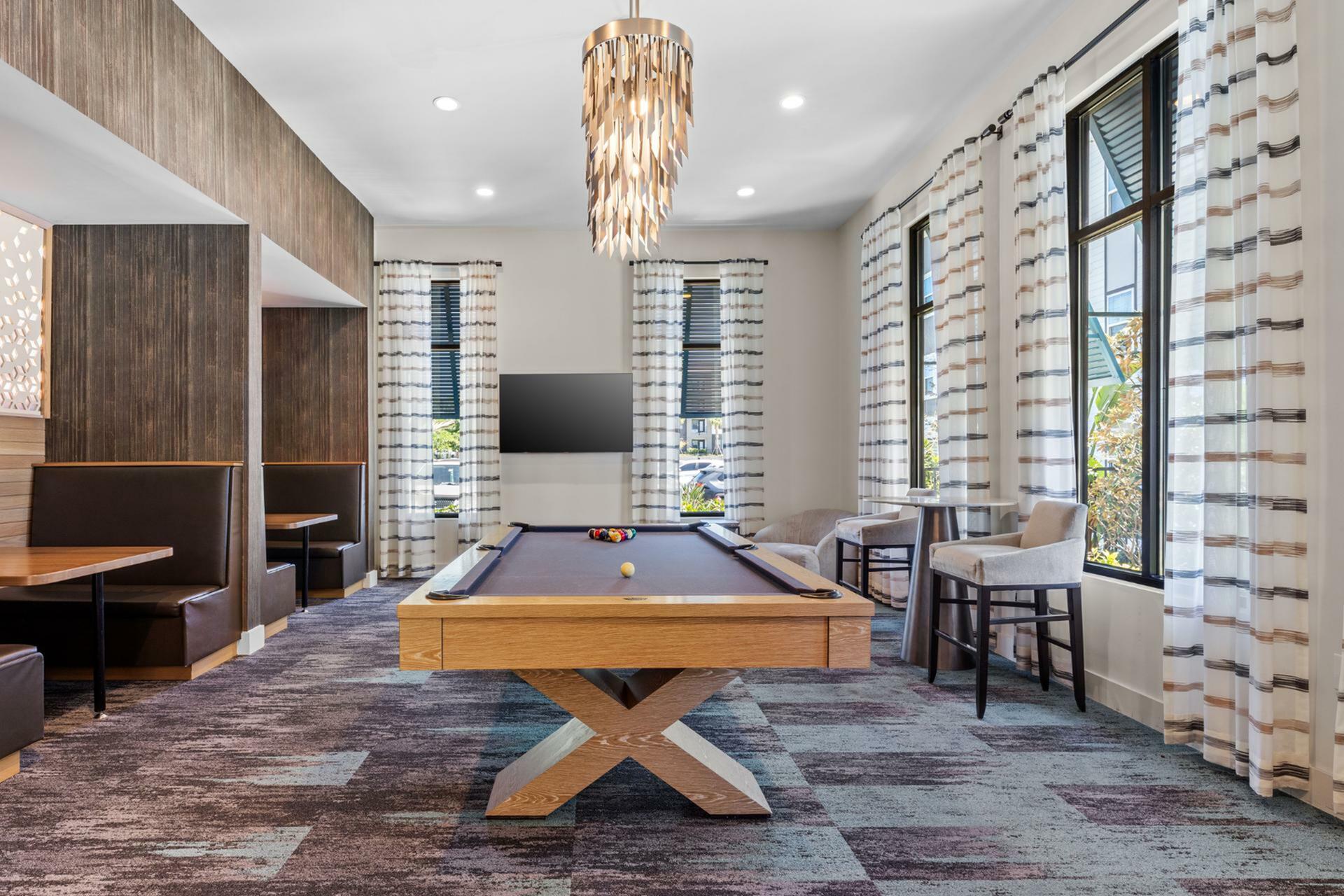Elegant recreation room with a stylish pool table, cozy seating areas, and contemporary lighting, perfect for leisure and entertainment.