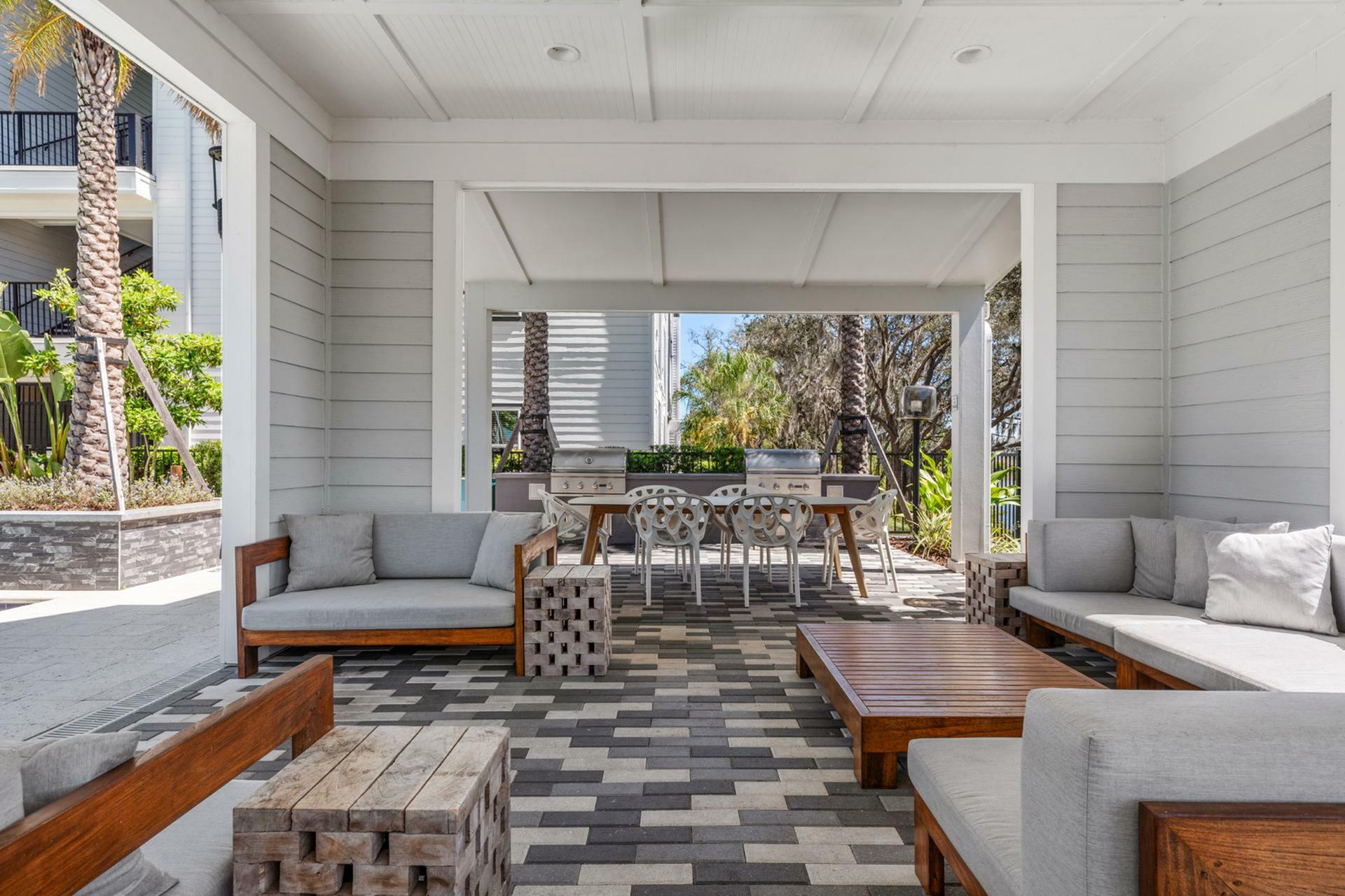 outdoor lounge with couches and tables and gas barbecue grill stations