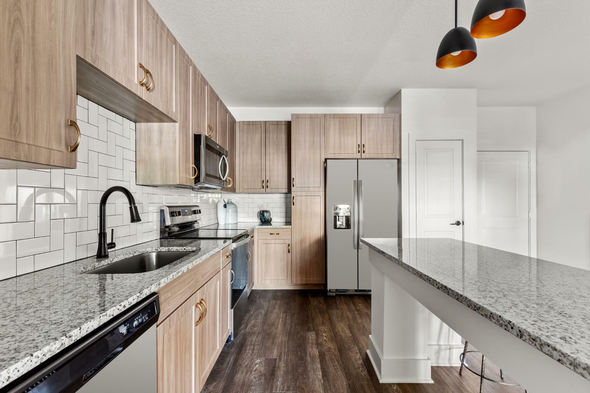 Modern kitchen design with elegant wood cabinetry, sleek granite countertops, and stainless steel appliances, complemented by stylish pendant lighting.