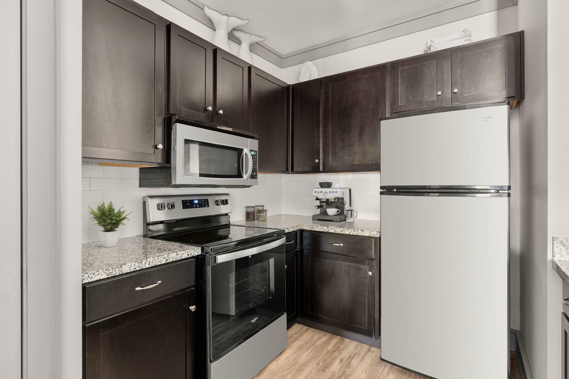 Modern kitchen with dark wood cabinets, sleek appliances, and stylish granite countertops, perfect for home chefs.