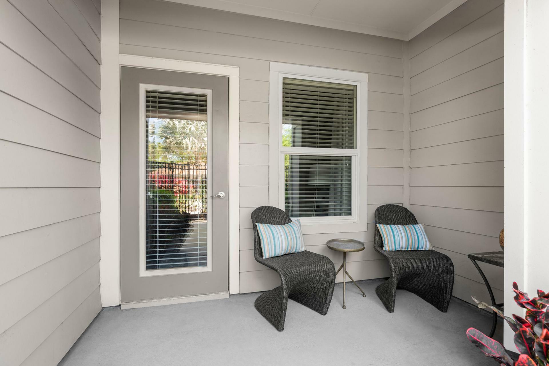 Charming patio space featuring modern wicker chairs and a chic side table, perfect for outdoor relaxation.