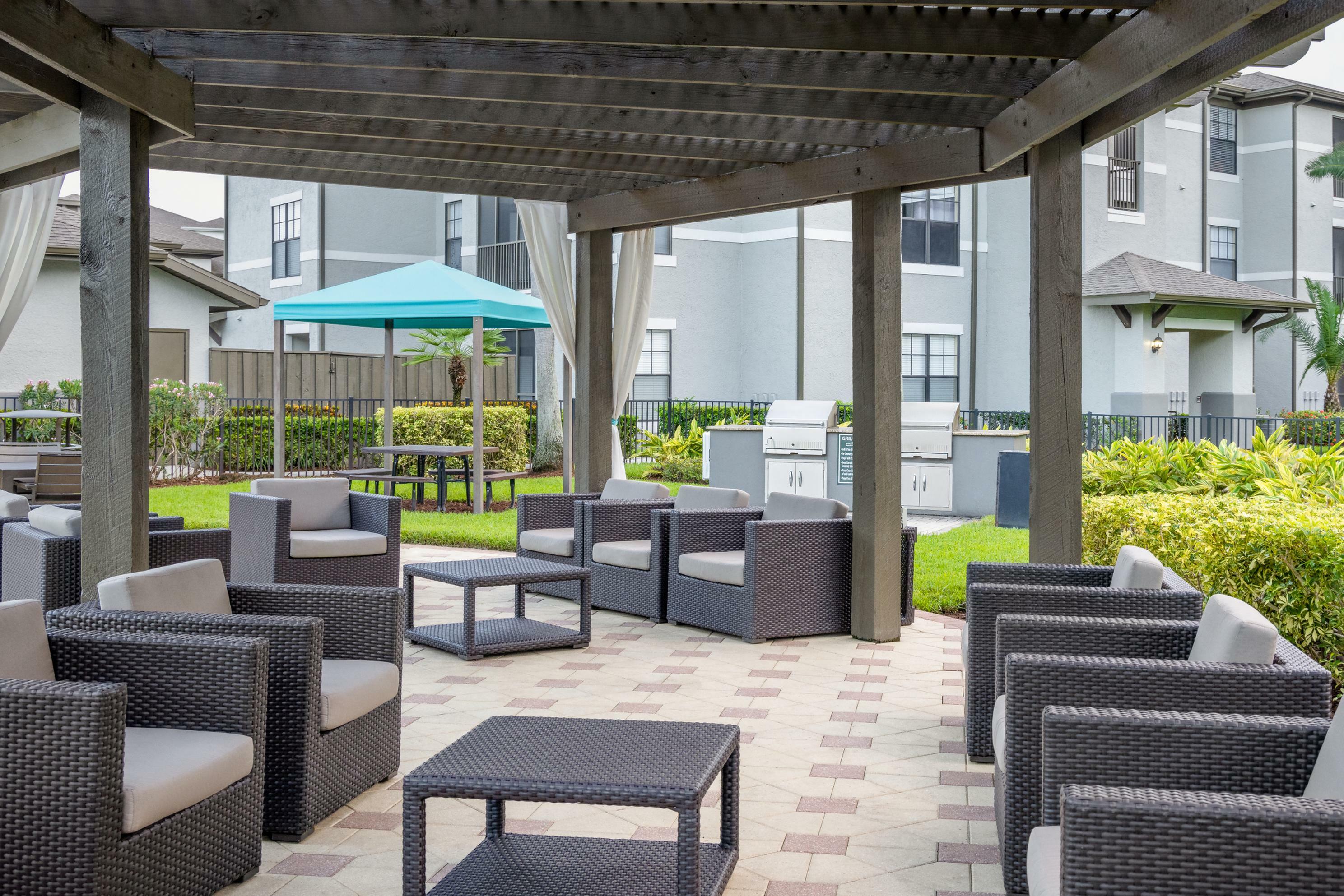 Charming outdoor patio area with modern wicker furniture, perfect for social gatherings under a stylish pergola with lush greenery surroundings.