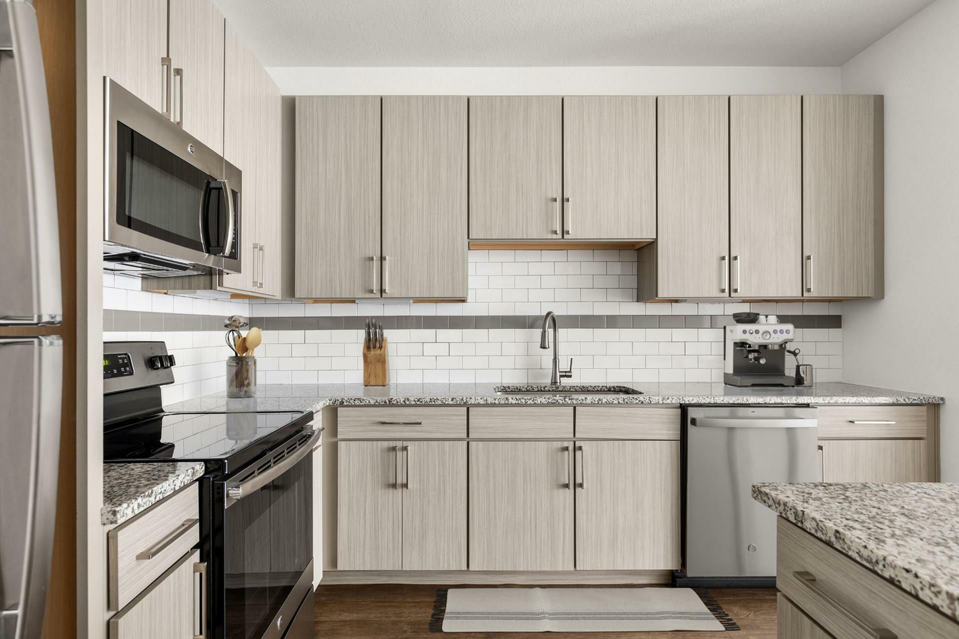 Sleek modern kitchen with stainless steel appliances, elegant granite countertops, and ample cabinetry. Perfect for culinary enthusiasts.