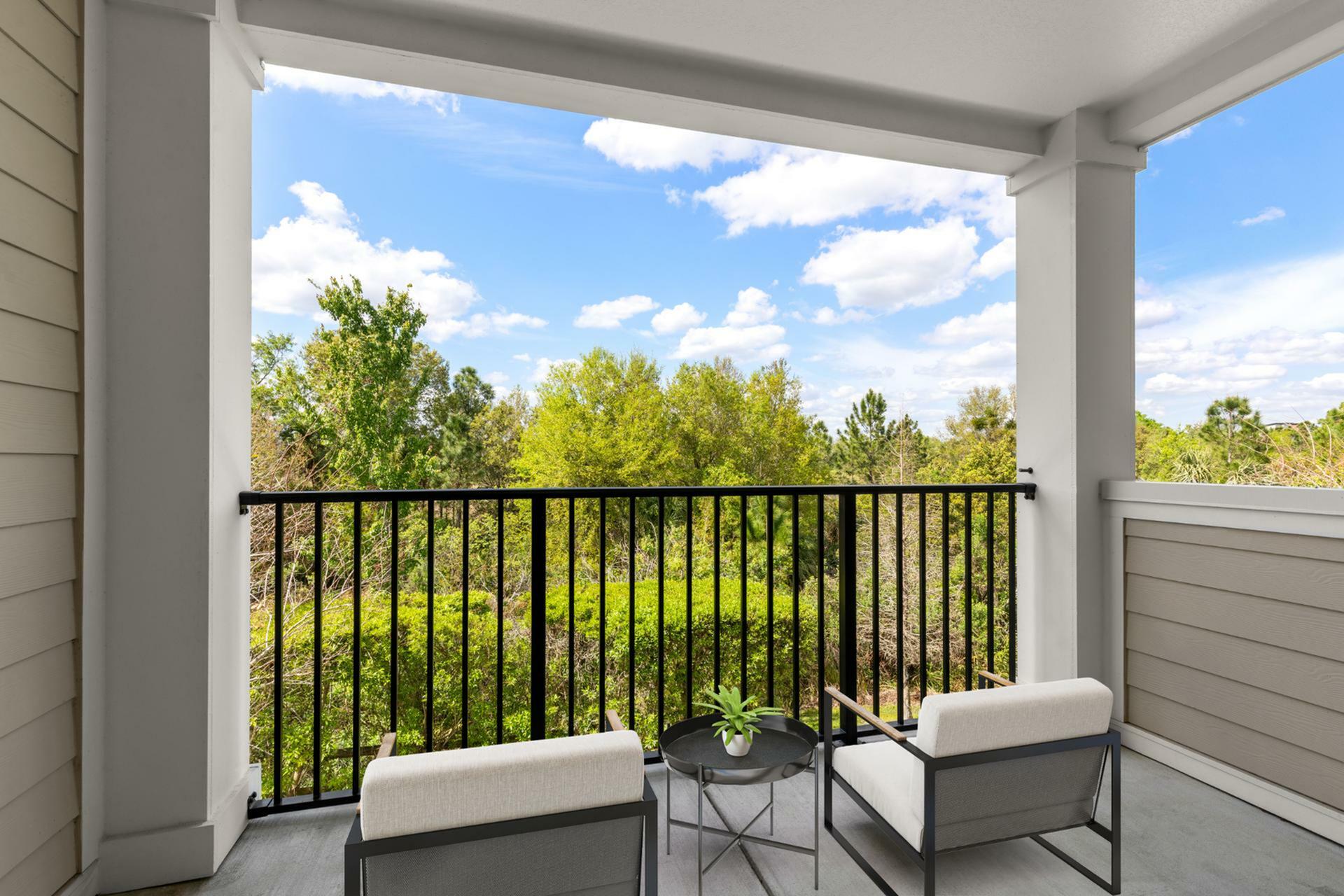 Charming balcony with cozy seating, showcasing stunning tree-filled views and blue skies, perfect for relaxation and enjoying nature.