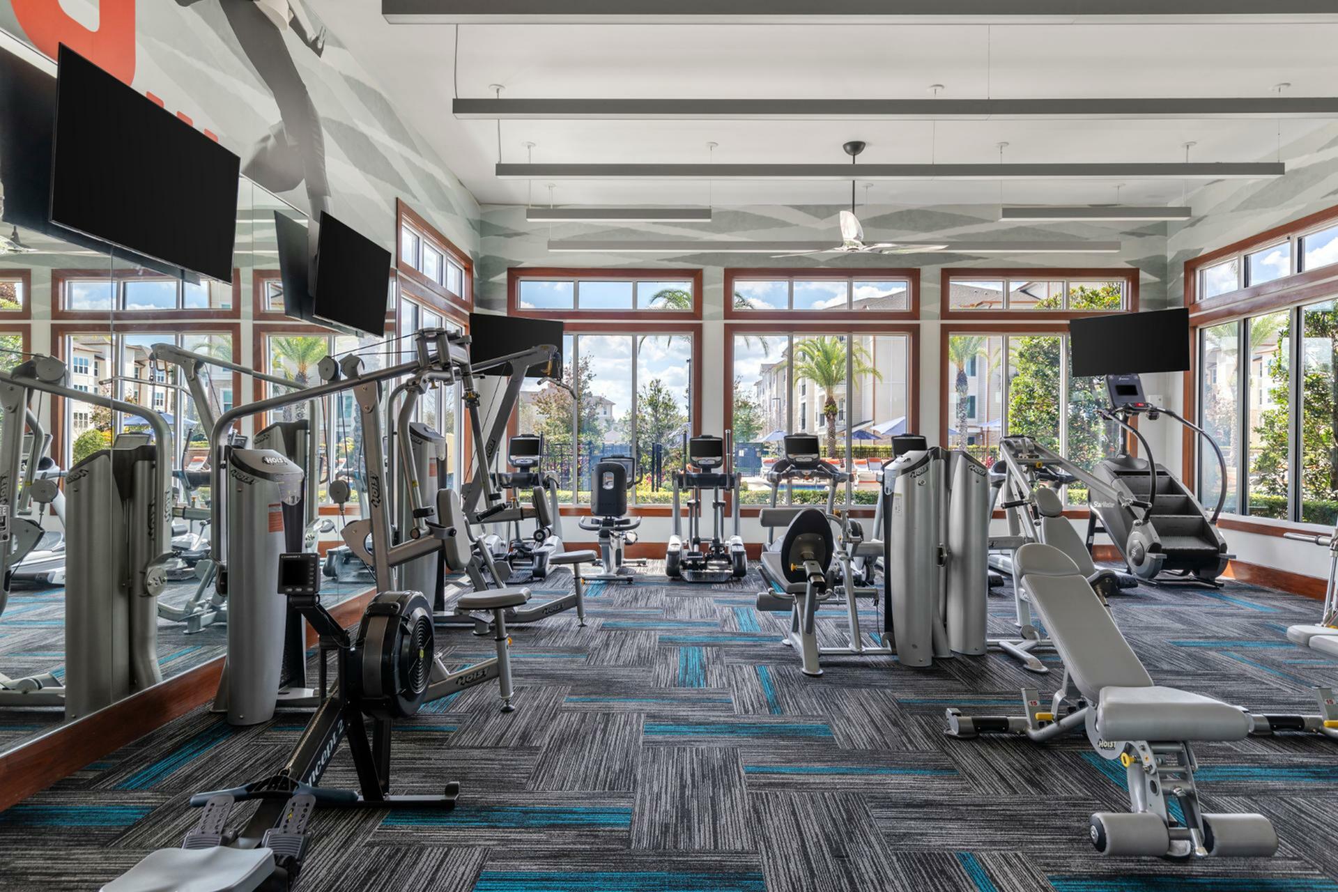 Modern fitness center with state-of-the-art gym equipment and large windows offering scenic outdoor views.