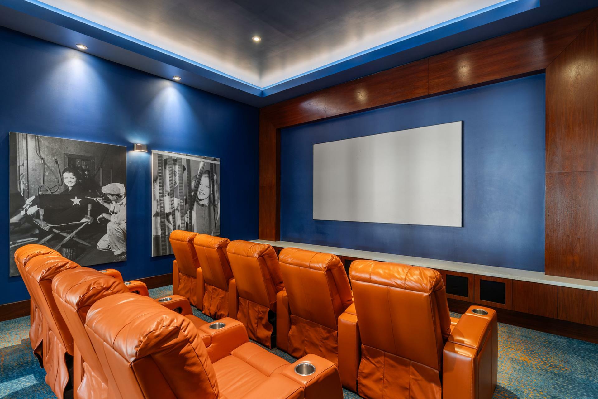 Luxurious home theater with plush orange recliners, elegant blue walls, and vintage decor for an ultimate cinematic experience.