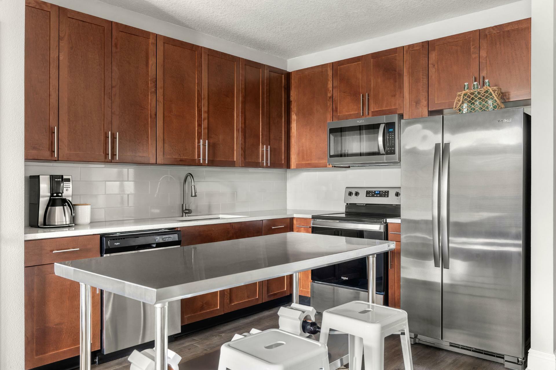 Modern kitchen with sleek stainless steel appliances, rich wooden cabinetry, and a stylish island with bar stools.