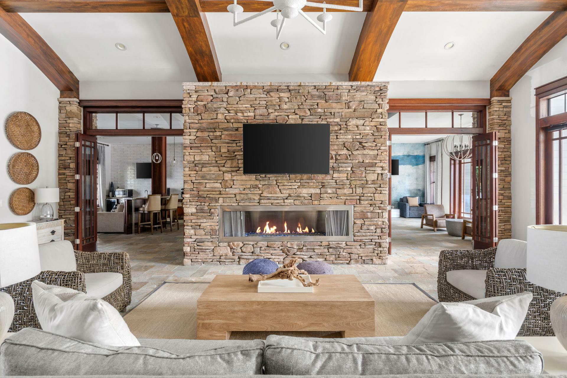 Luxurious living room with a modern stone fireplace, ceiling fan, and cozy seating; ideal for stylish relaxation.