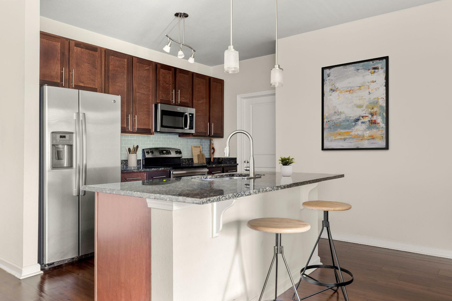 Contemporary kitchen with sleek granite countertops, stainless steel appliances, and stylish pendant lighting.