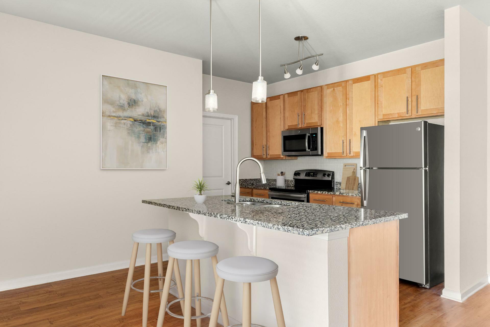 Modern kitchen with sleek granite countertops, stainless steel appliances, and cozy bar seating, accented by elegant pendant lights.