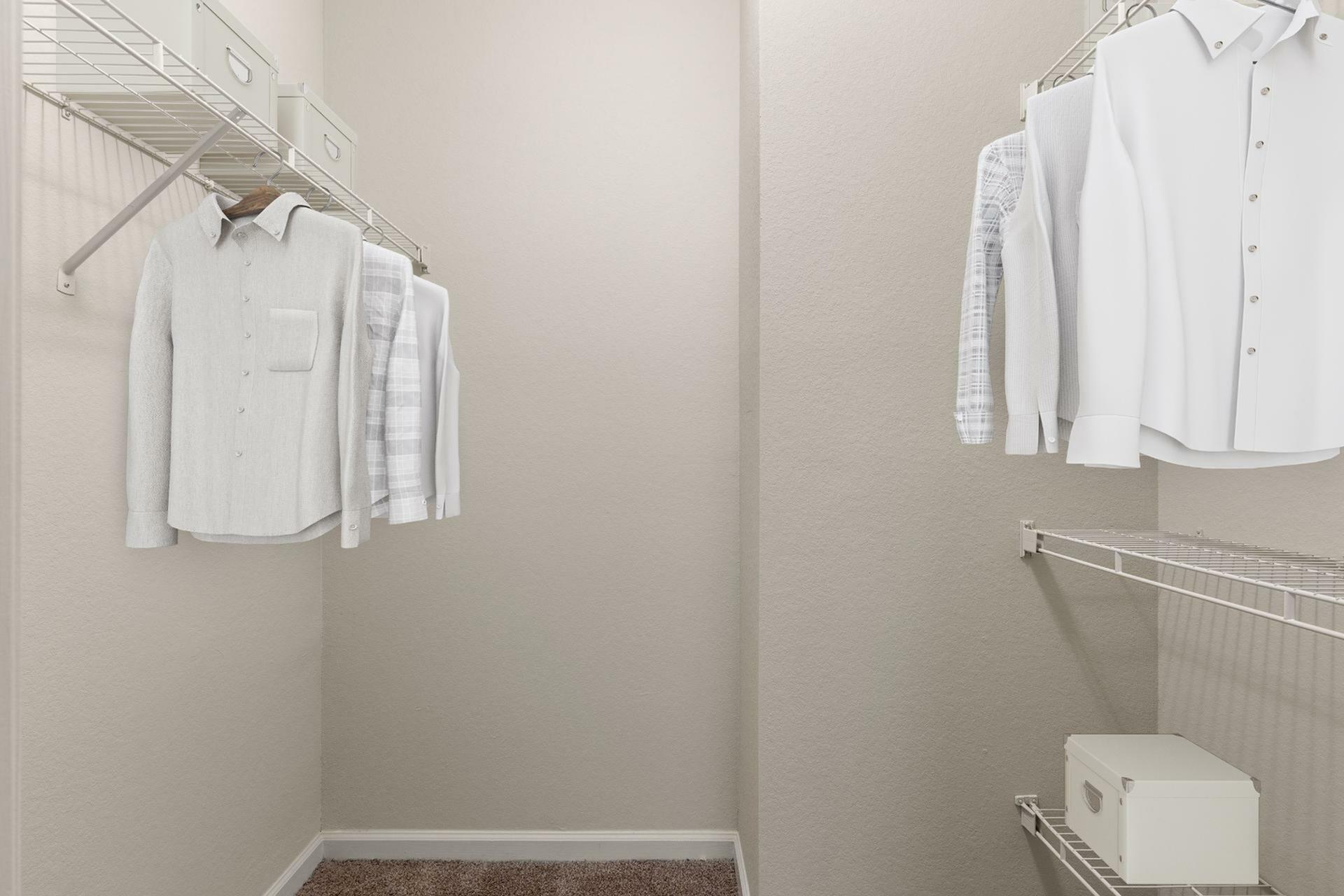 Spacious walk-in closet with wire shelving, neatly organized clothing, and a minimalist style.