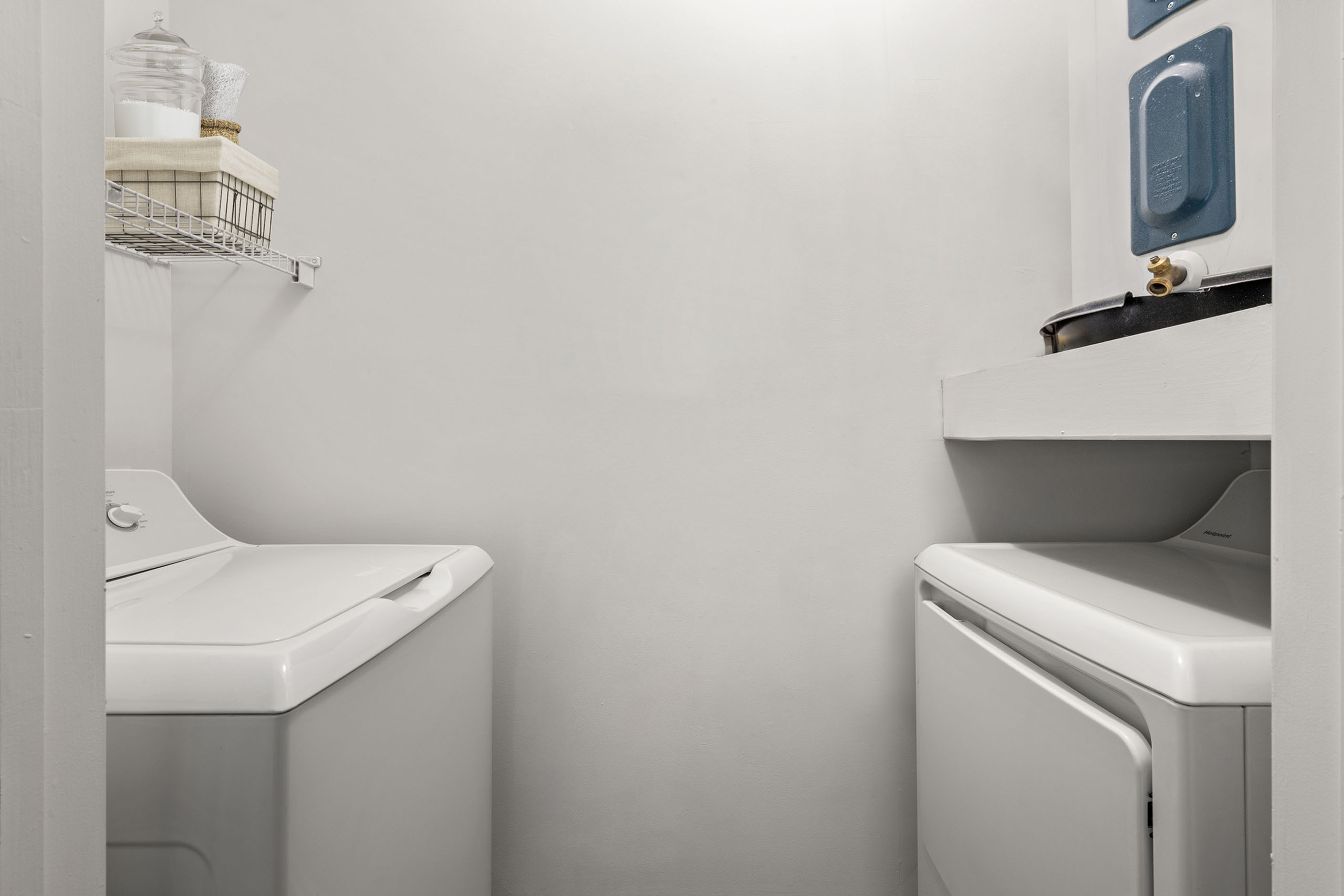 Modern laundry room with sleek washer and dryer, featuring minimalist shelving and organized storage.