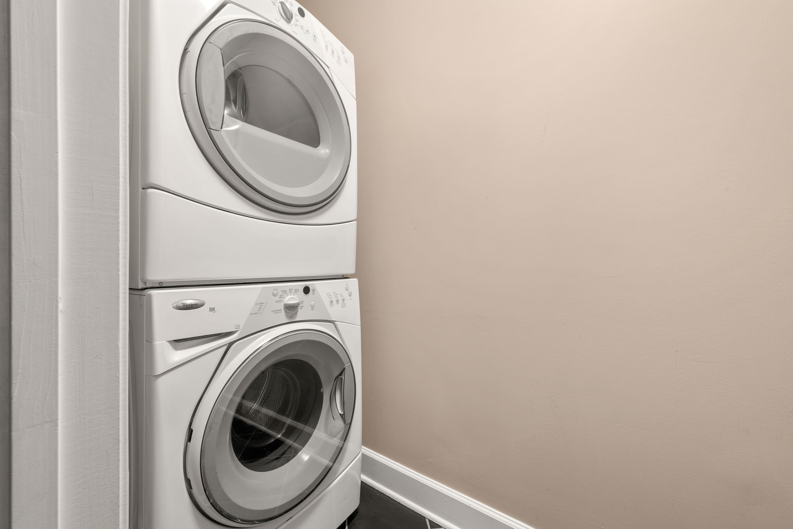 Modern laundry area featuring a stacked front-load washer and dryer set against a clean, neutral-toned wall.