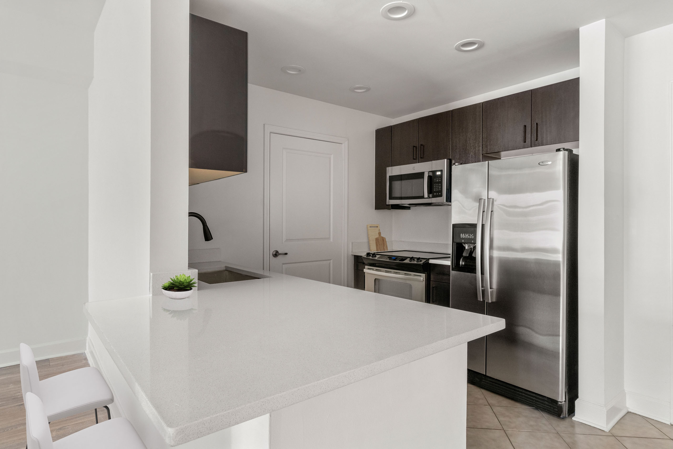Modern kitchen with sleek stainless steel appliances, quartz countertops, and stylish dark cabinetry.