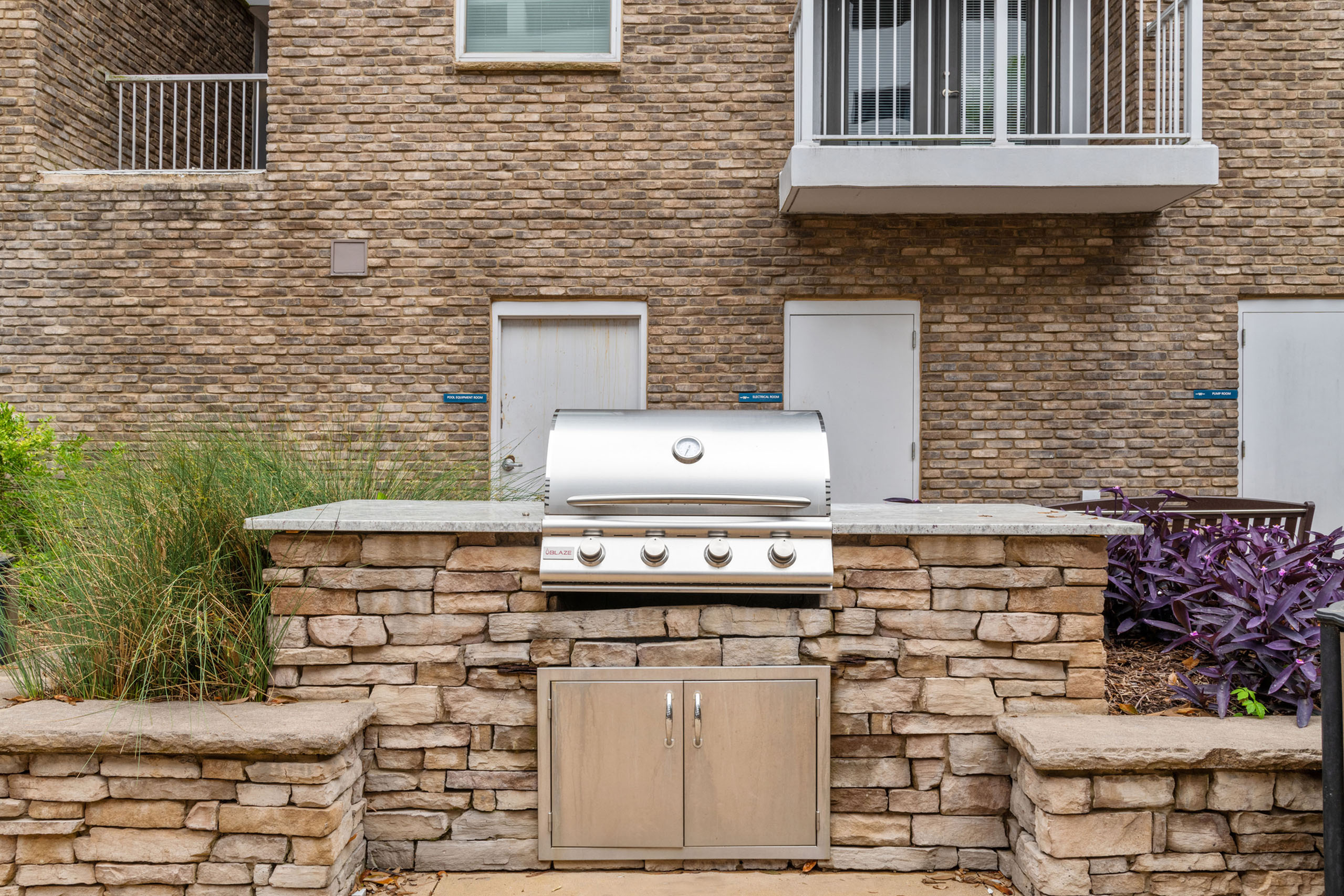 Charming outdoor patio area featuring a sleek stainless steel grill set against rustic brick walls, perfect for entertaining.