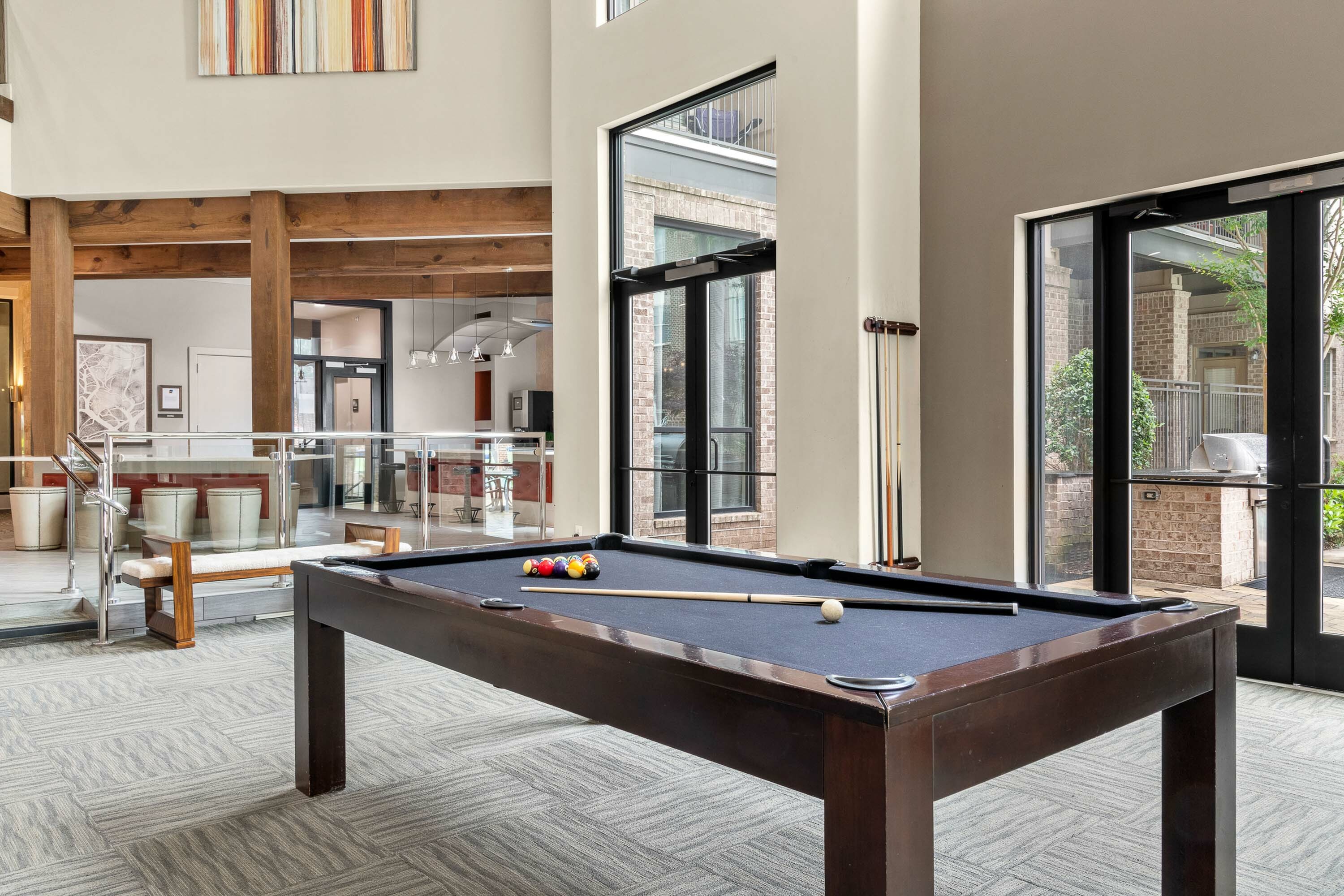 Inviting recreation space featuring a stylish pool table, modern decor, and bright natural lighting.