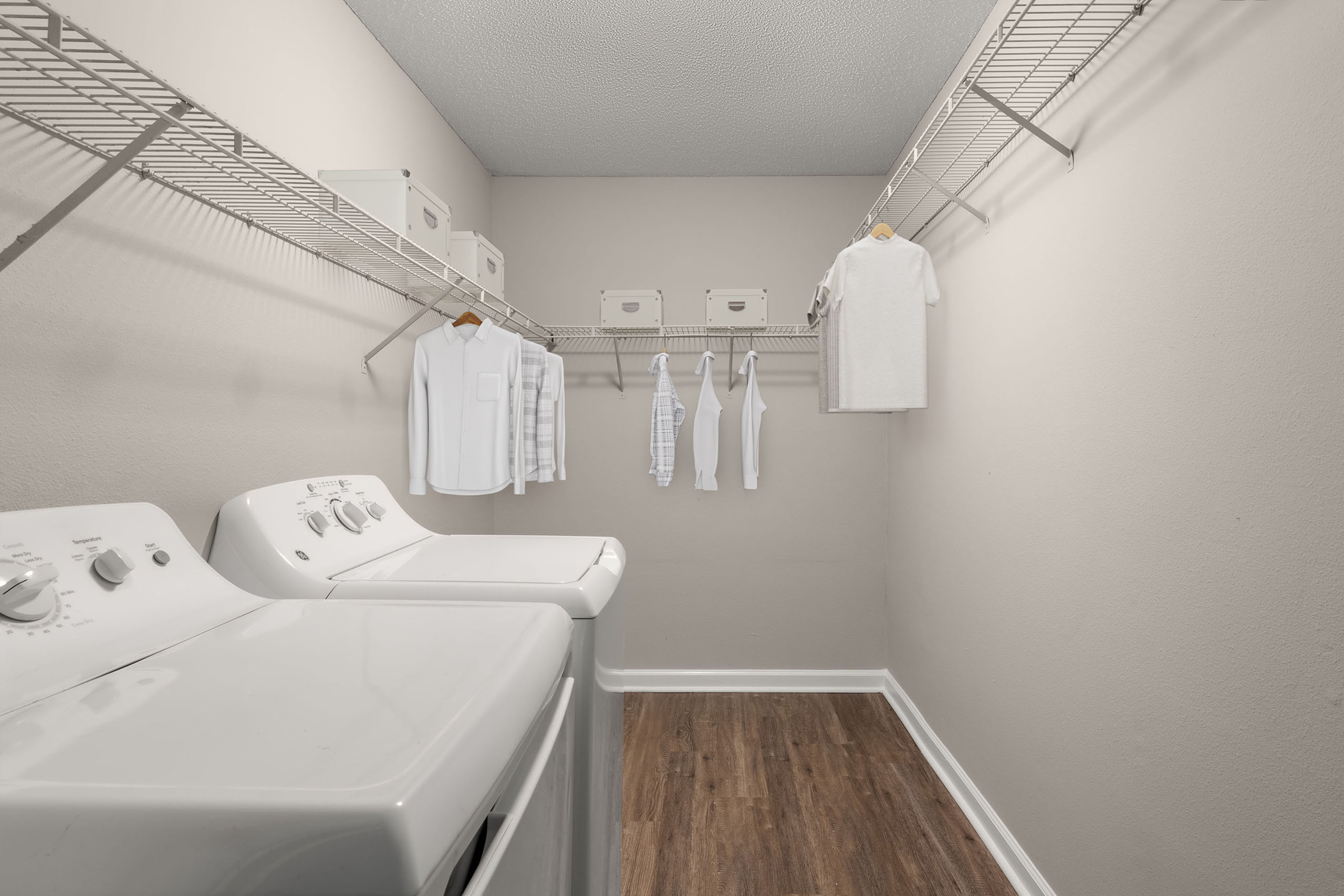 Spacious laundry room with washer, dryer, and ample shelving, featuring stylish hanging storage for seamless organization.
