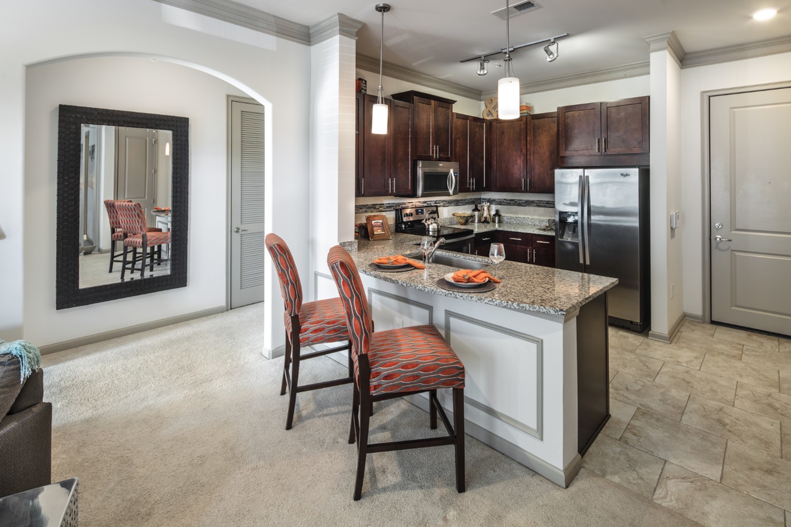 Chic kitchen with granite countertops and stylish pendant lighting, featuring modern appliances and comfy bar stools for casual dining.