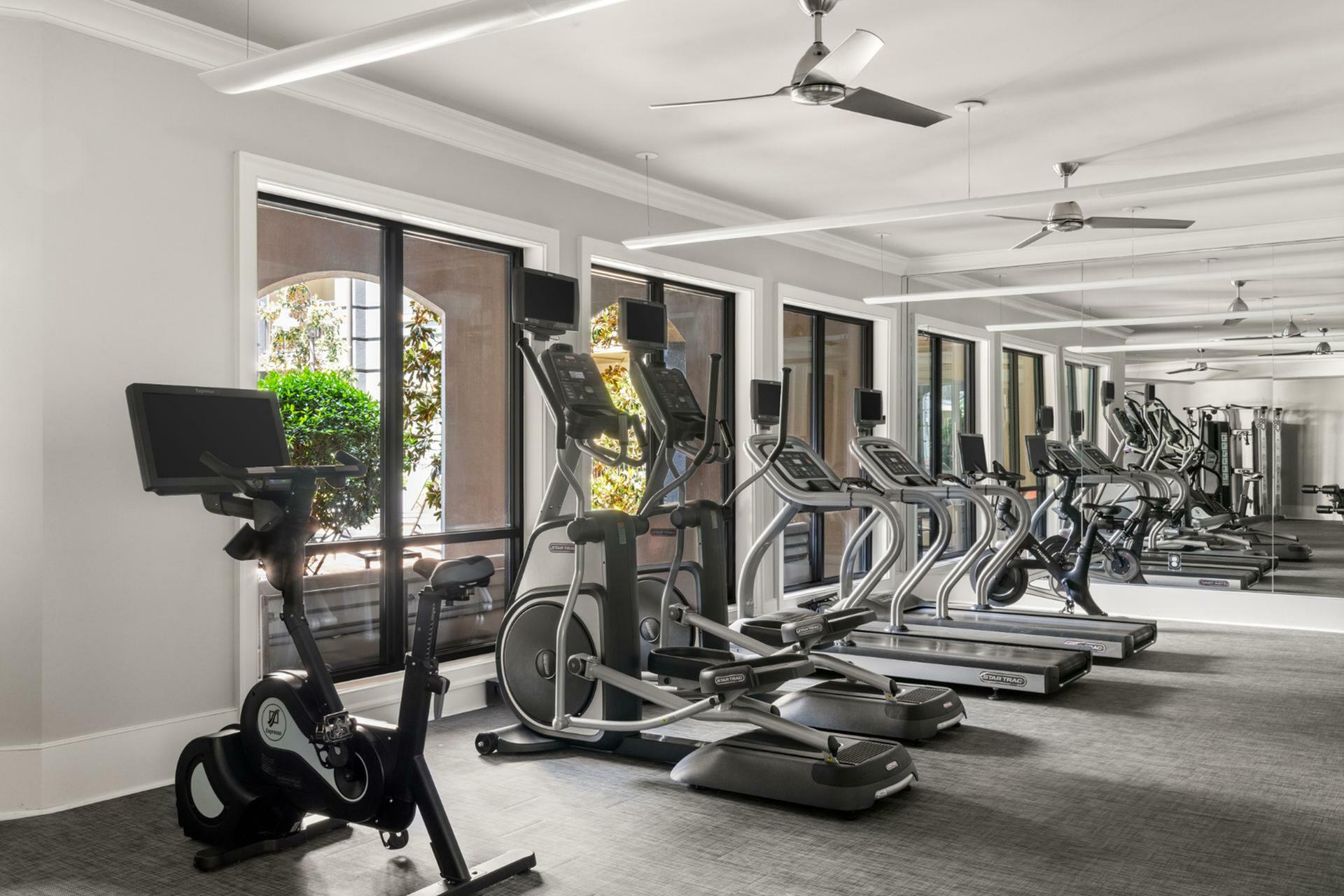 Modern fitness center with state-of-the-art exercise equipment, bright windows, and sleek interior design.