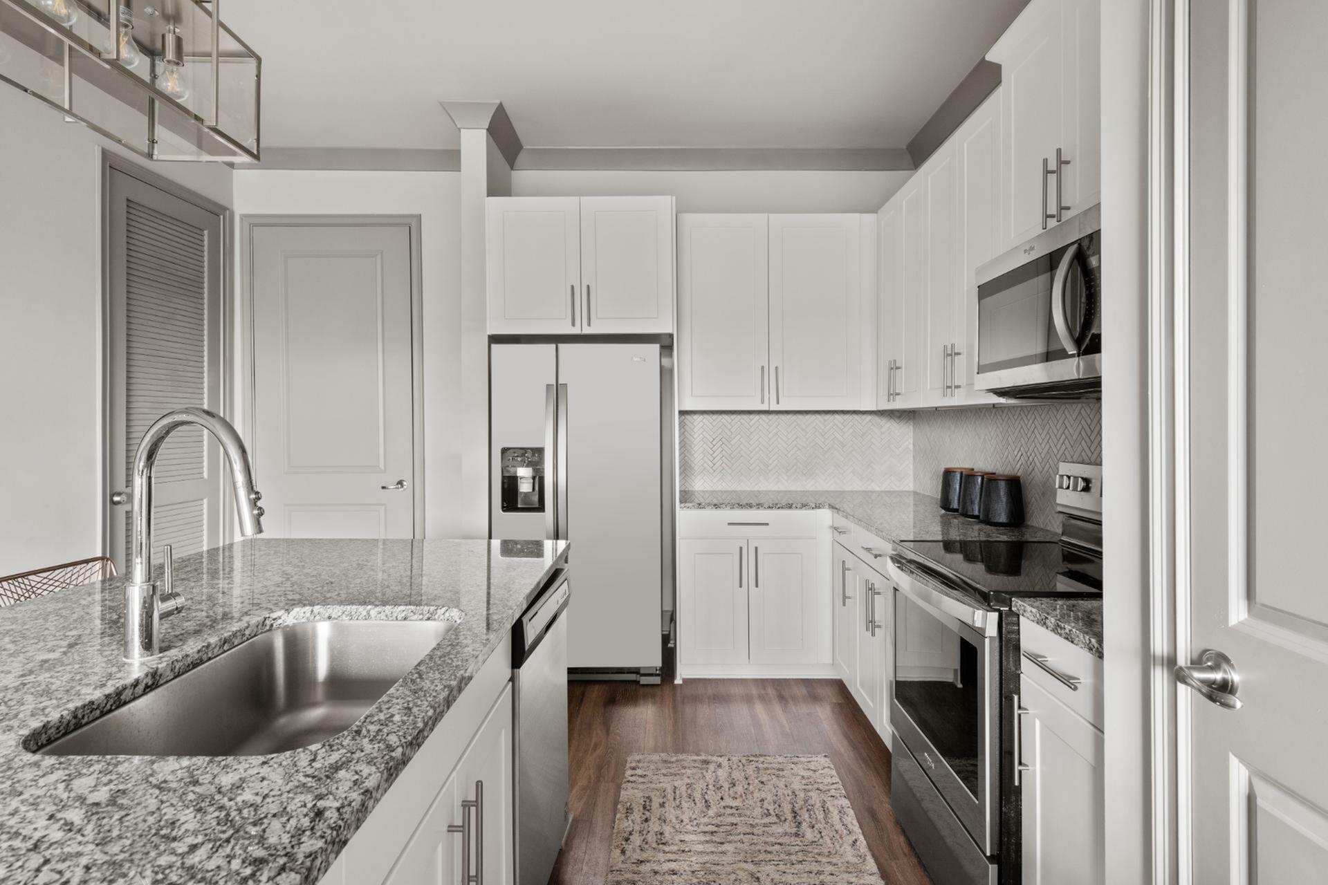 Sleek modern kitchen with granite countertops, stainless steel appliances, and elegant white cabinetry.