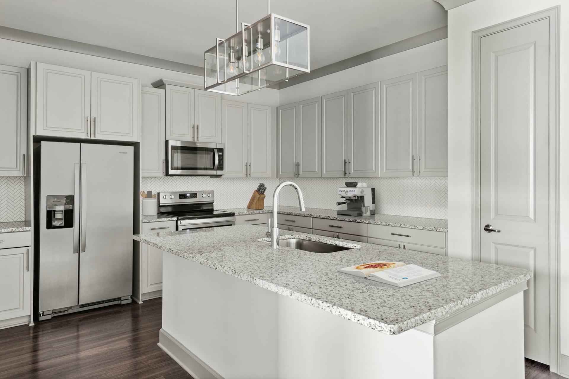 Elegant modern kitchen with sleek white cabinetry, stainless steel appliances, and a spacious granite island, perfect for culinary adventures.