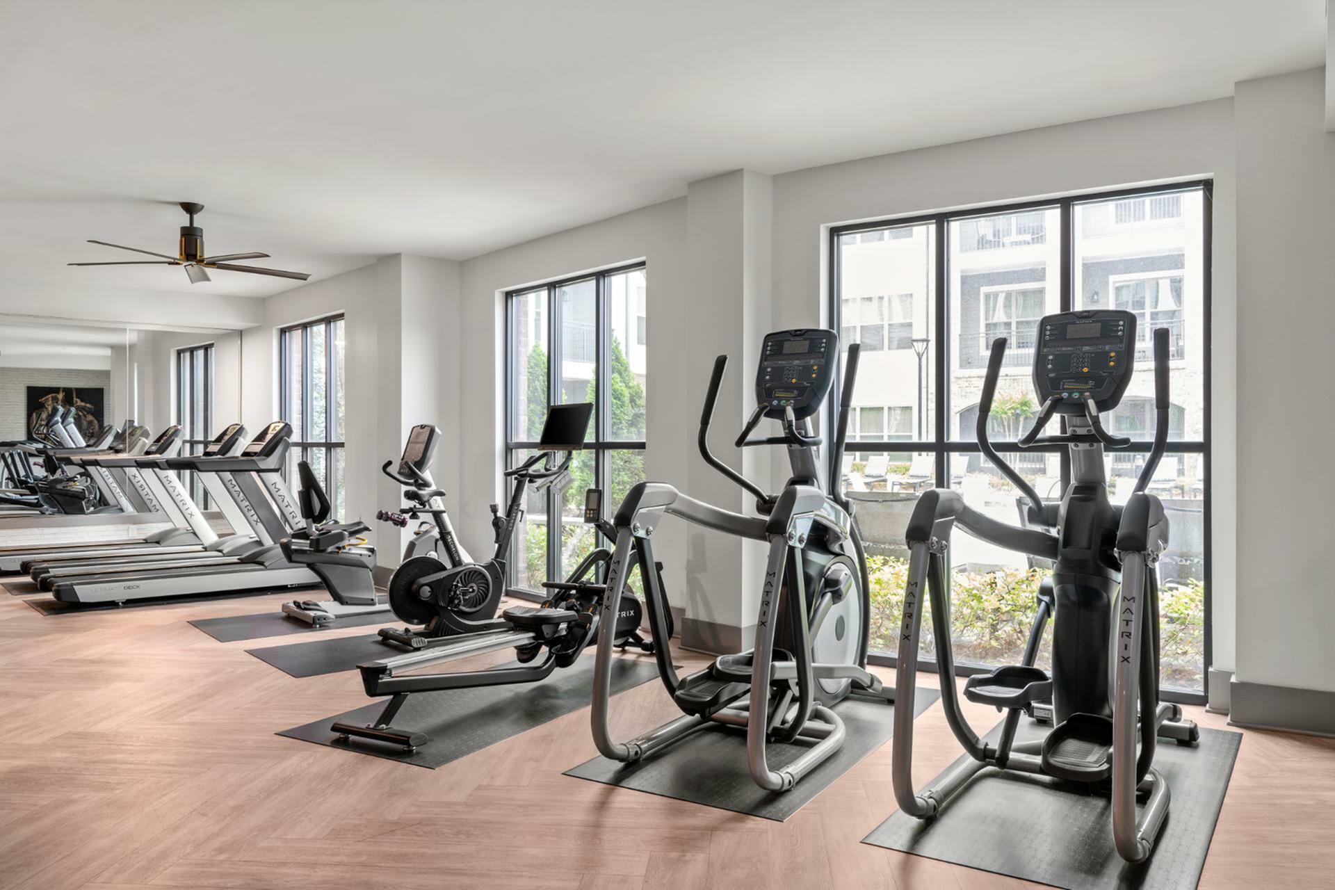 Bright, modern fitness center with state-of-the-art exercise machines and large windows offering a scenic view.