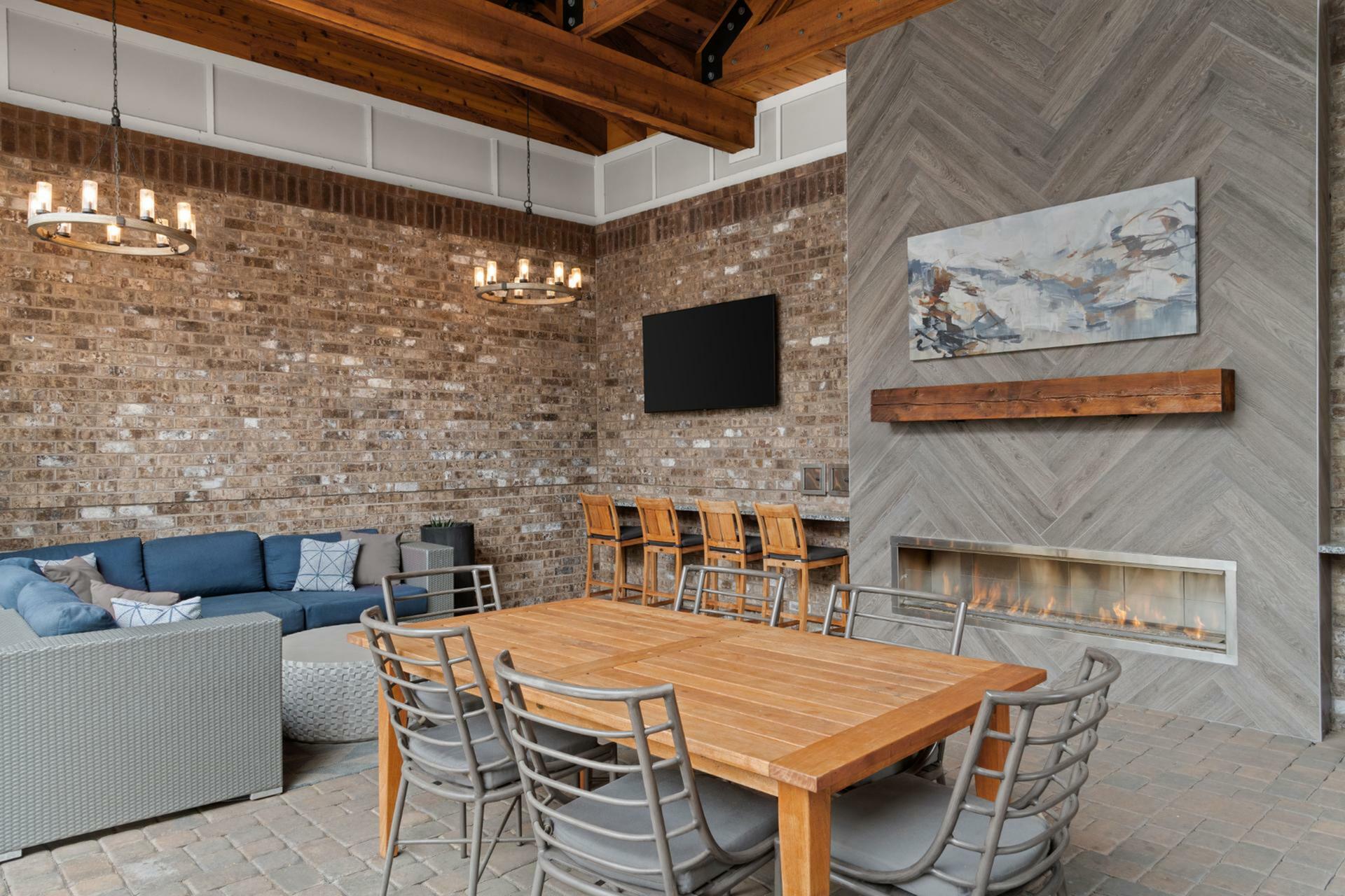 Chic and cozy indoor lounge with rustic brick walls, a modern fireplace, and stylish seating, perfect for relaxation and gatherings.