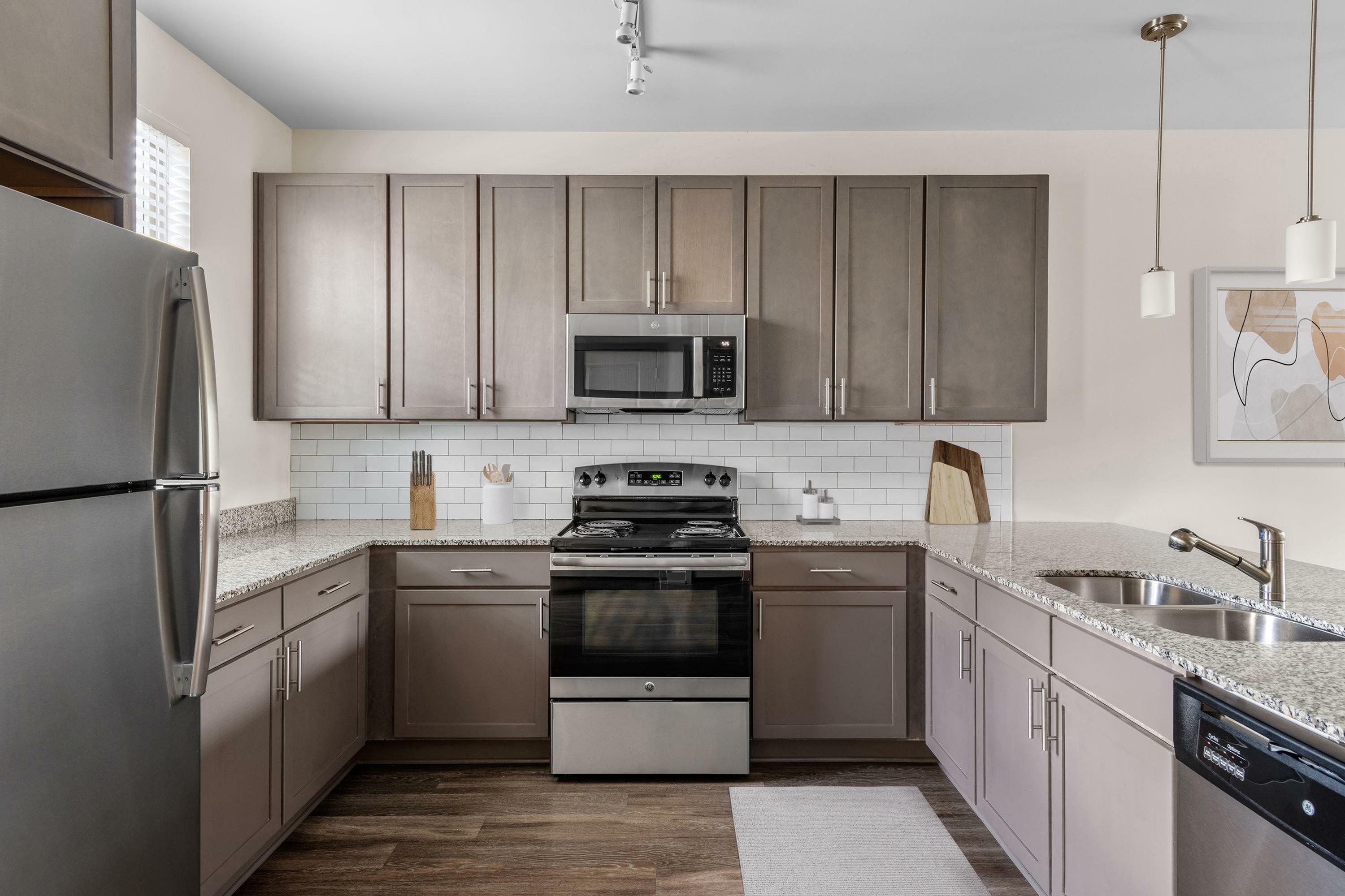 Modern kitchen with sleek grey cabinets, granite countertops, stainless steel appliances, and stylish track lighting.