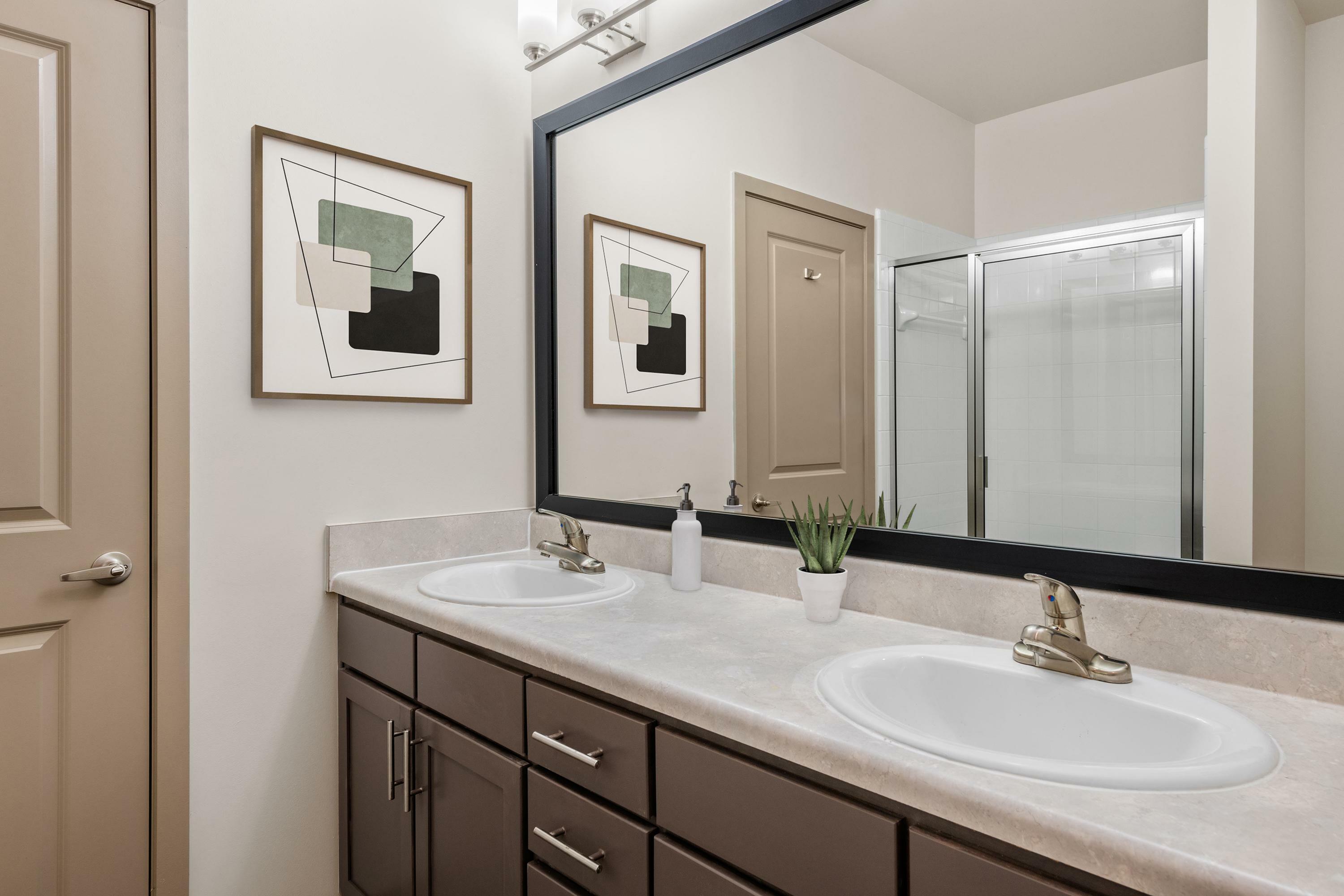 Elegant and modern bathroom featuring a double vanity with sleek fixtures, a large framed mirror, and minimalistic decor.