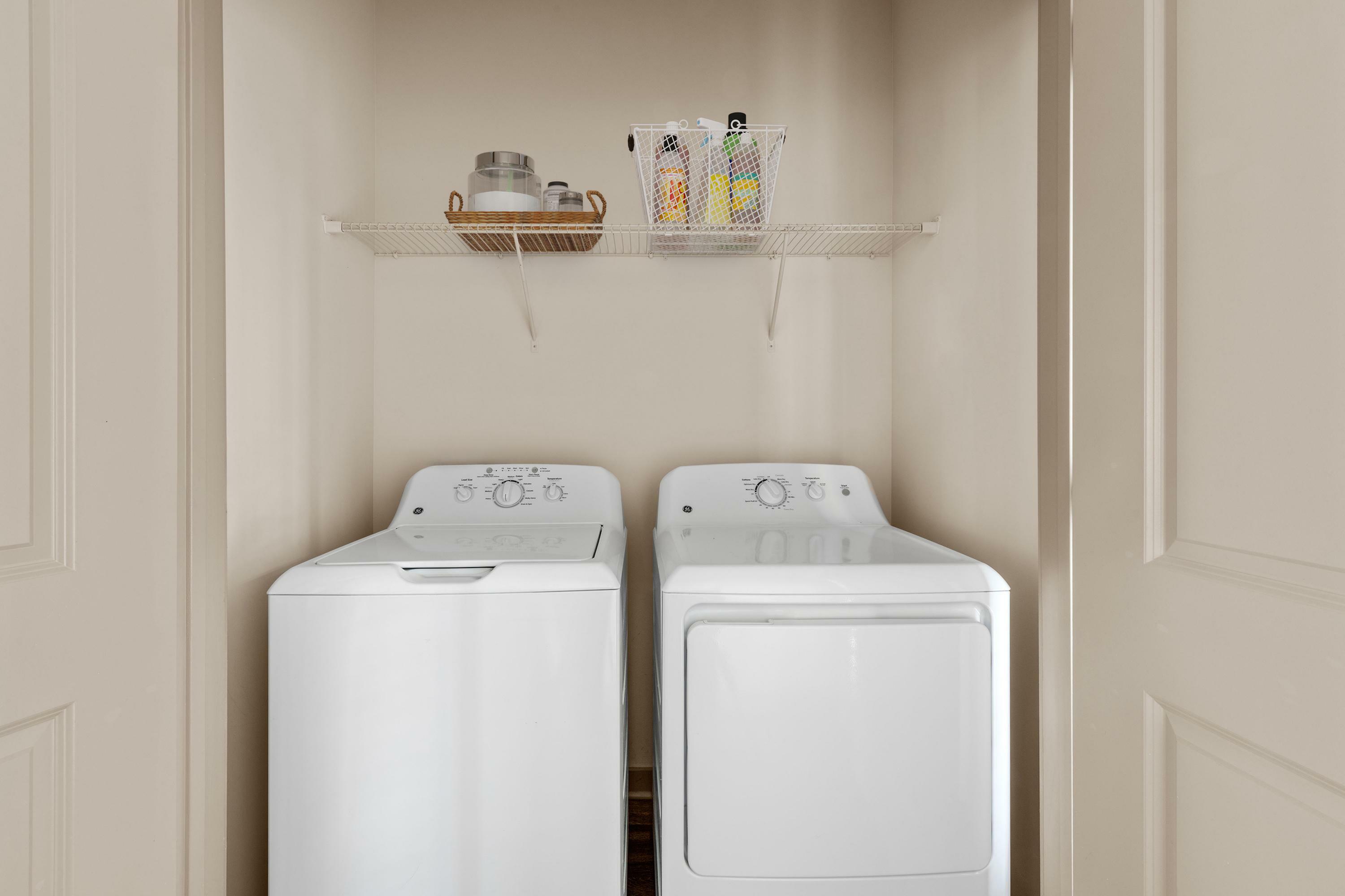 Modern laundry area with energy-efficient washer and dryer, complemented by ample storage shelving for convenience.