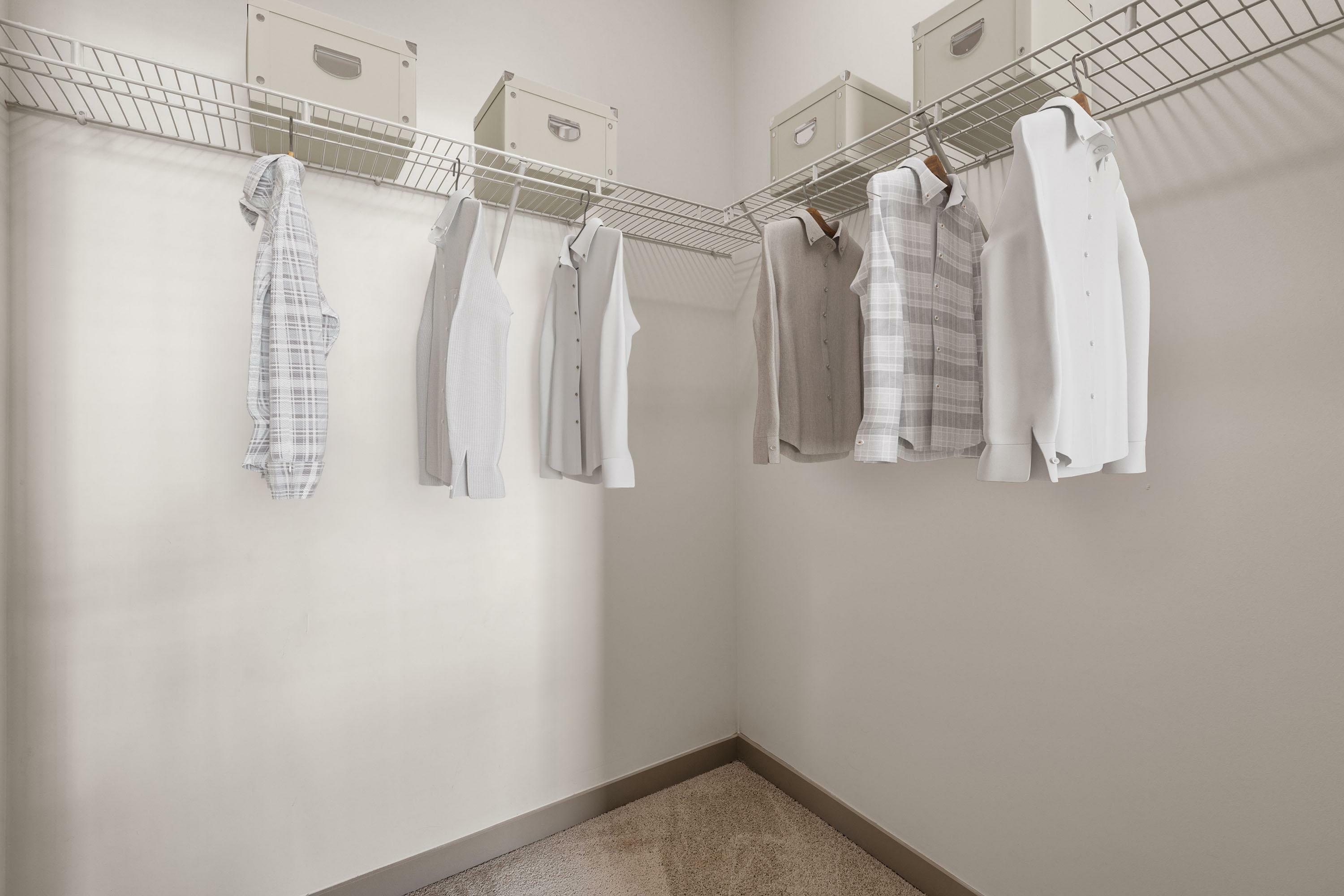 Spacious walk-in closet with neatly organized clothing and elegant storage boxes, offering refined elegance and functionality.