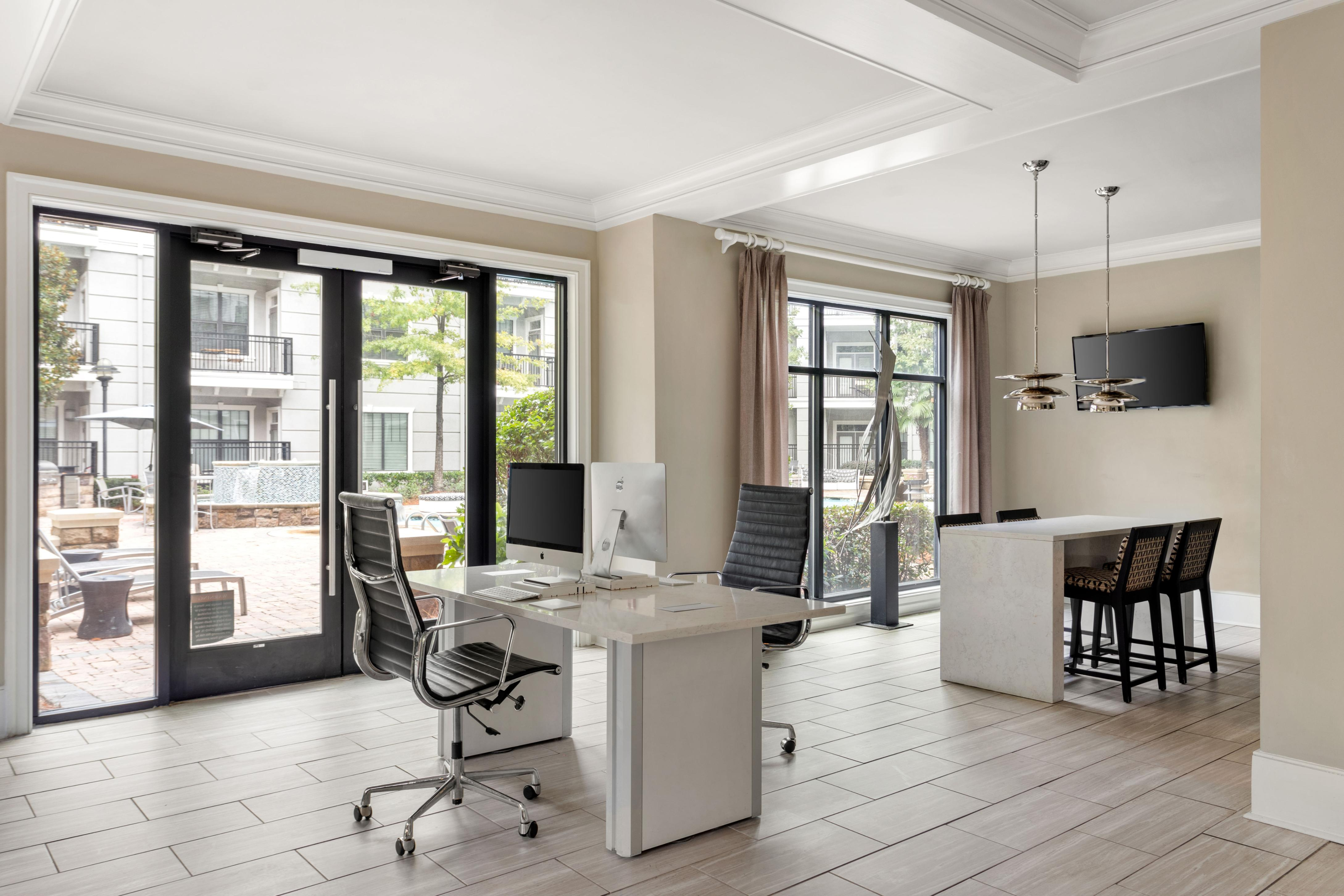 Modern workspace with sleek desk, ergonomic chairs, and large windows overlooking a beautifully landscaped courtyard.