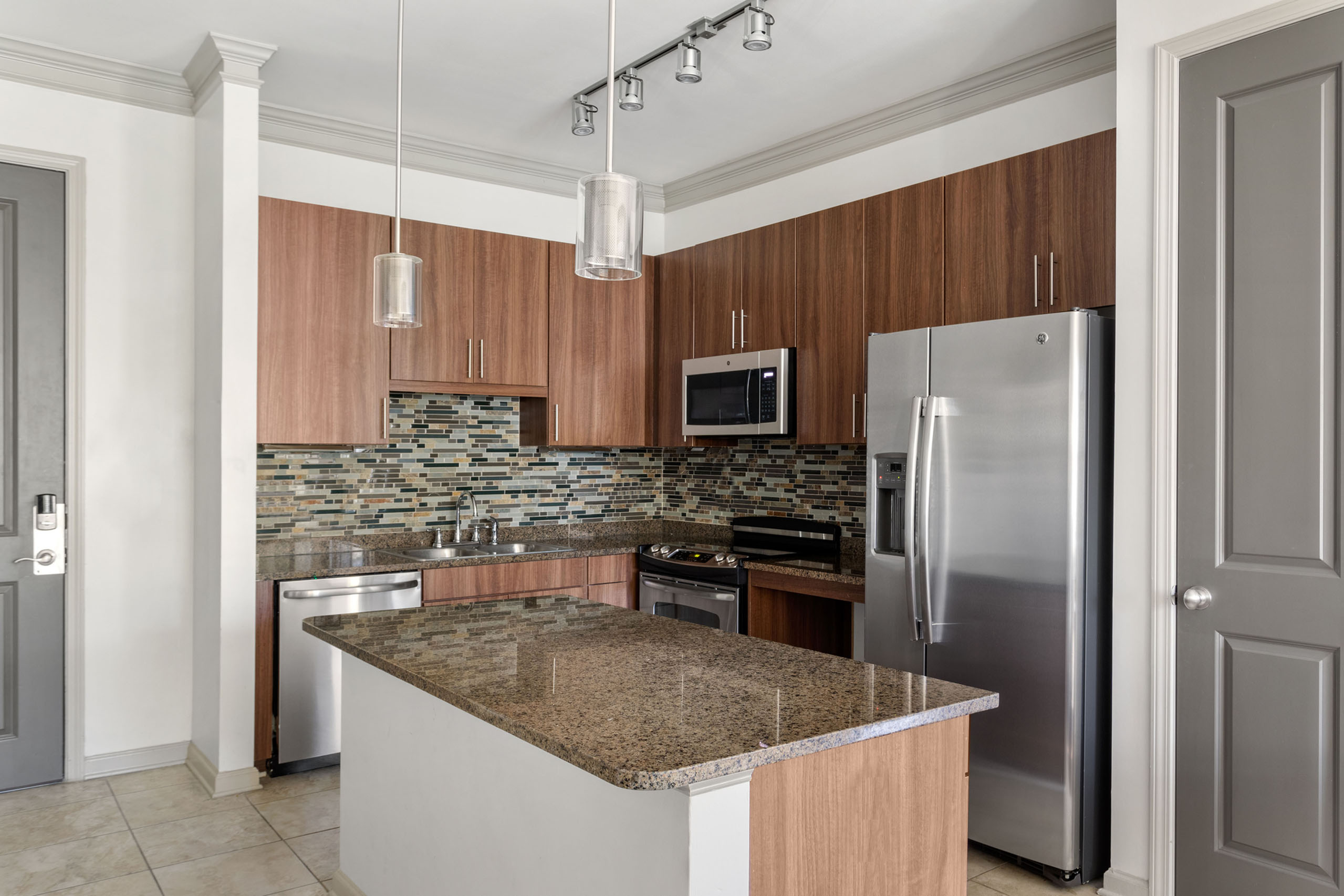 Modern kitchen with sleek stainless steel appliances, elegant granite countertops, and stylish mosaic backsplash.