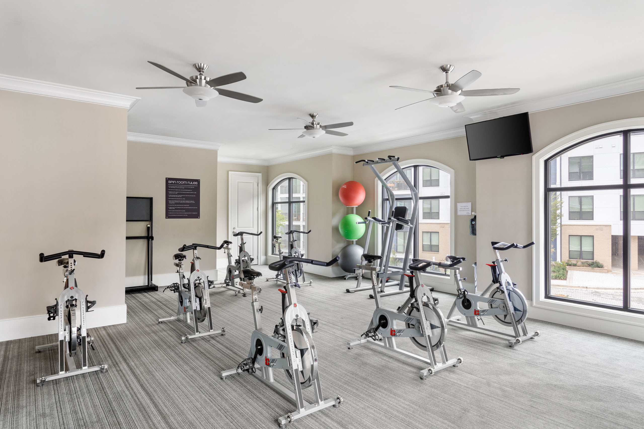 Modern fitness center featuring spin bikes, exercise equipment, and bright windows inviting natural light.