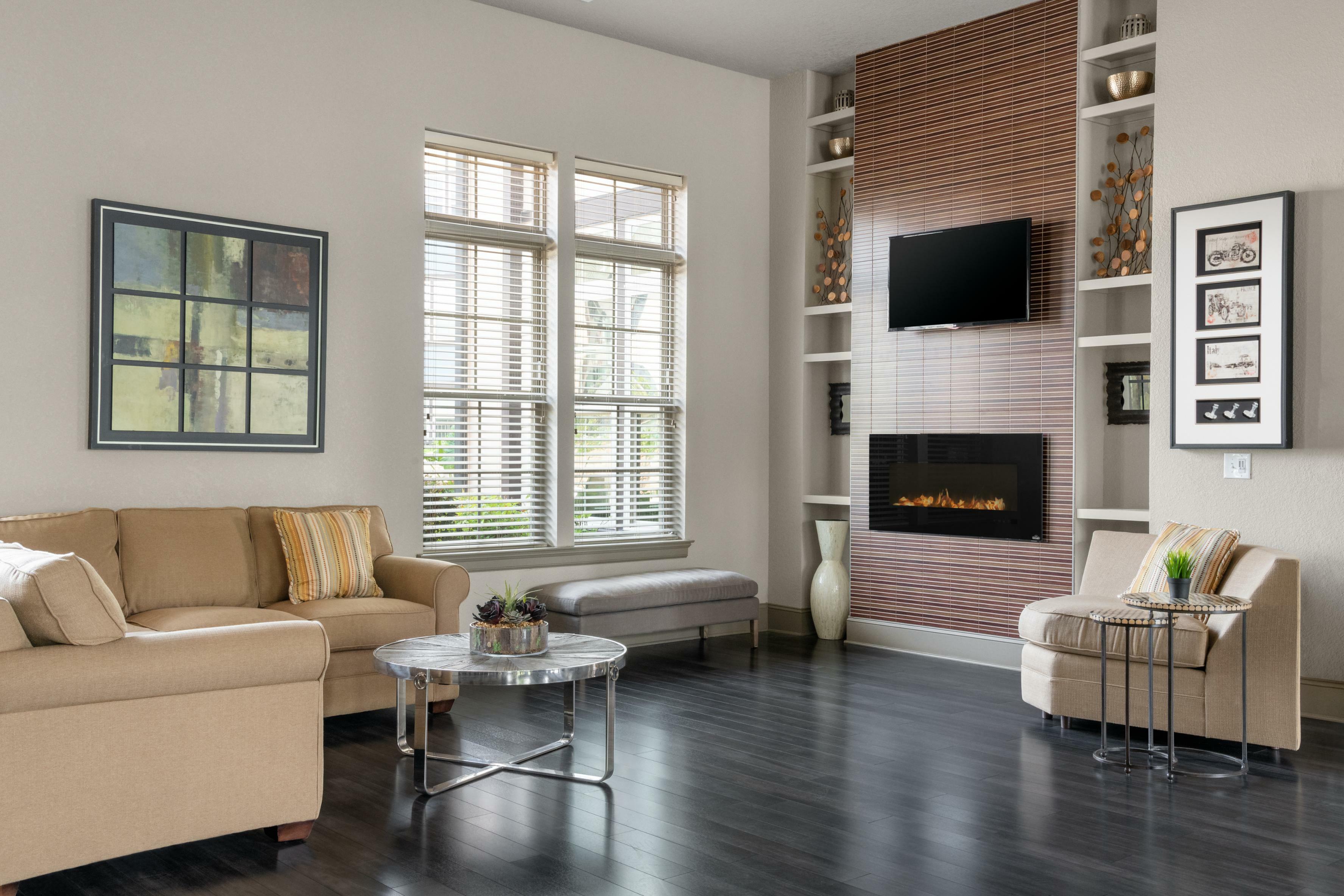 Chic living room featuring a cozy beige sofa, modern art, large windows, sleek fireplace, and stylish decor.