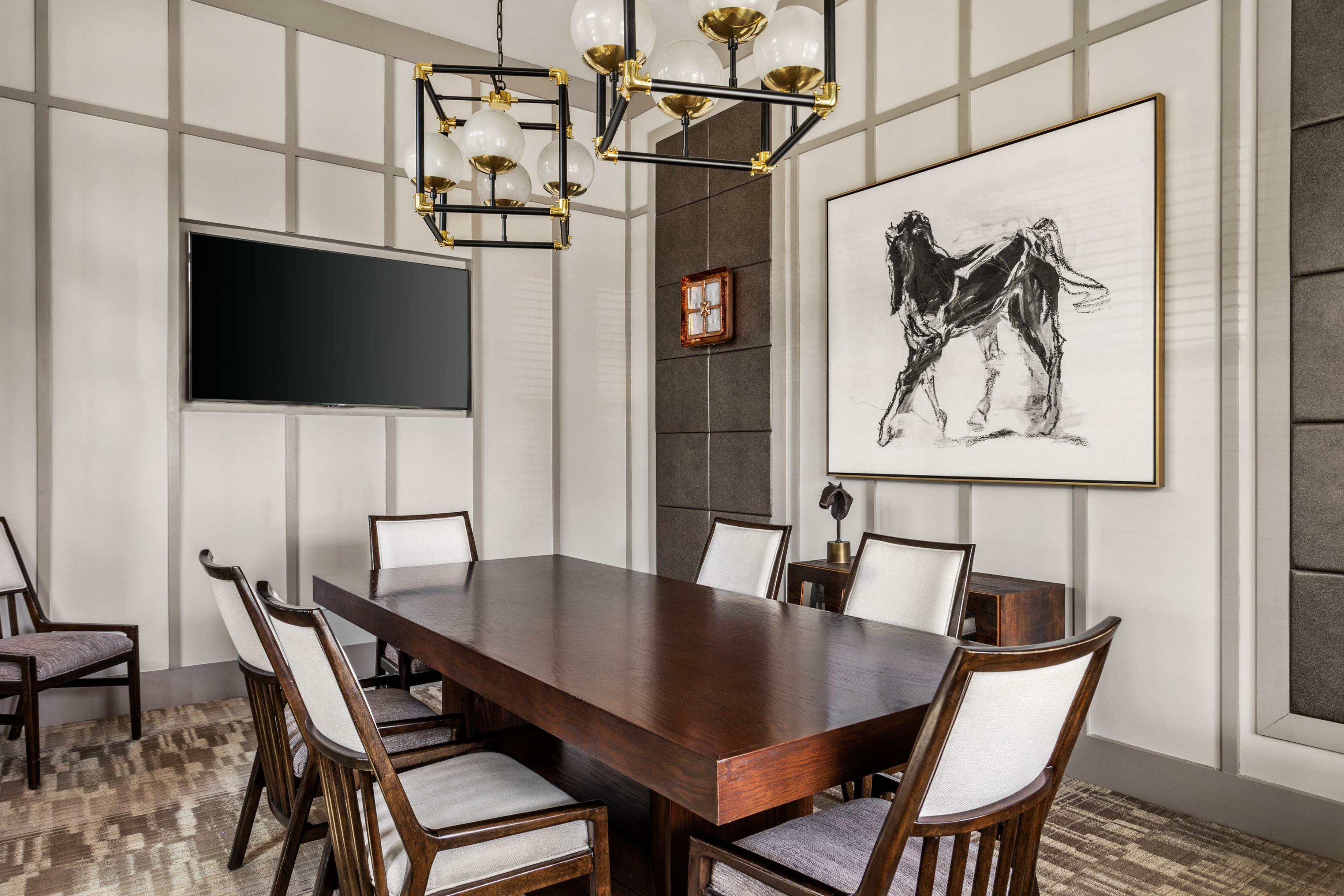 Elegant dining area with a chic wooden table, modern chandelier, and horse artwork, perfect for sophisticated gatherings.