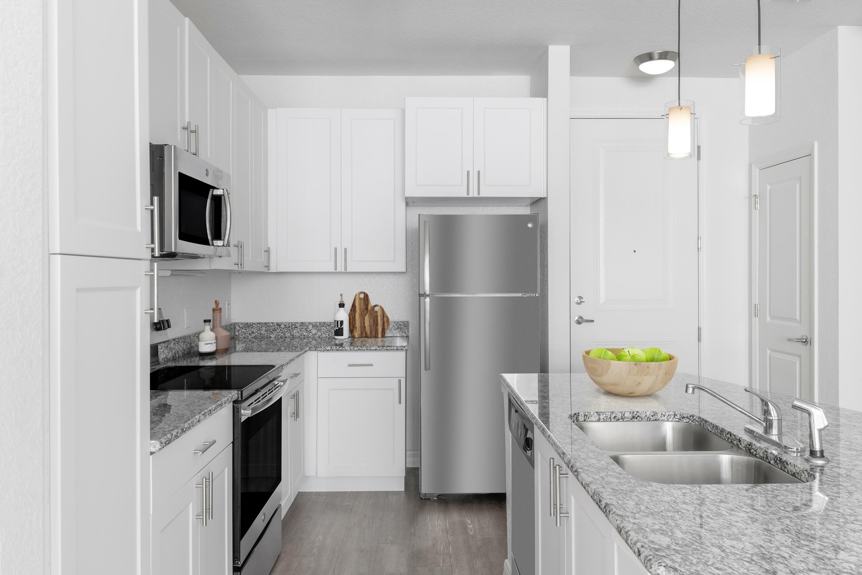 Sleek modern kitchen with granite countertops, stainless steel appliances, and stylish white cabinets.