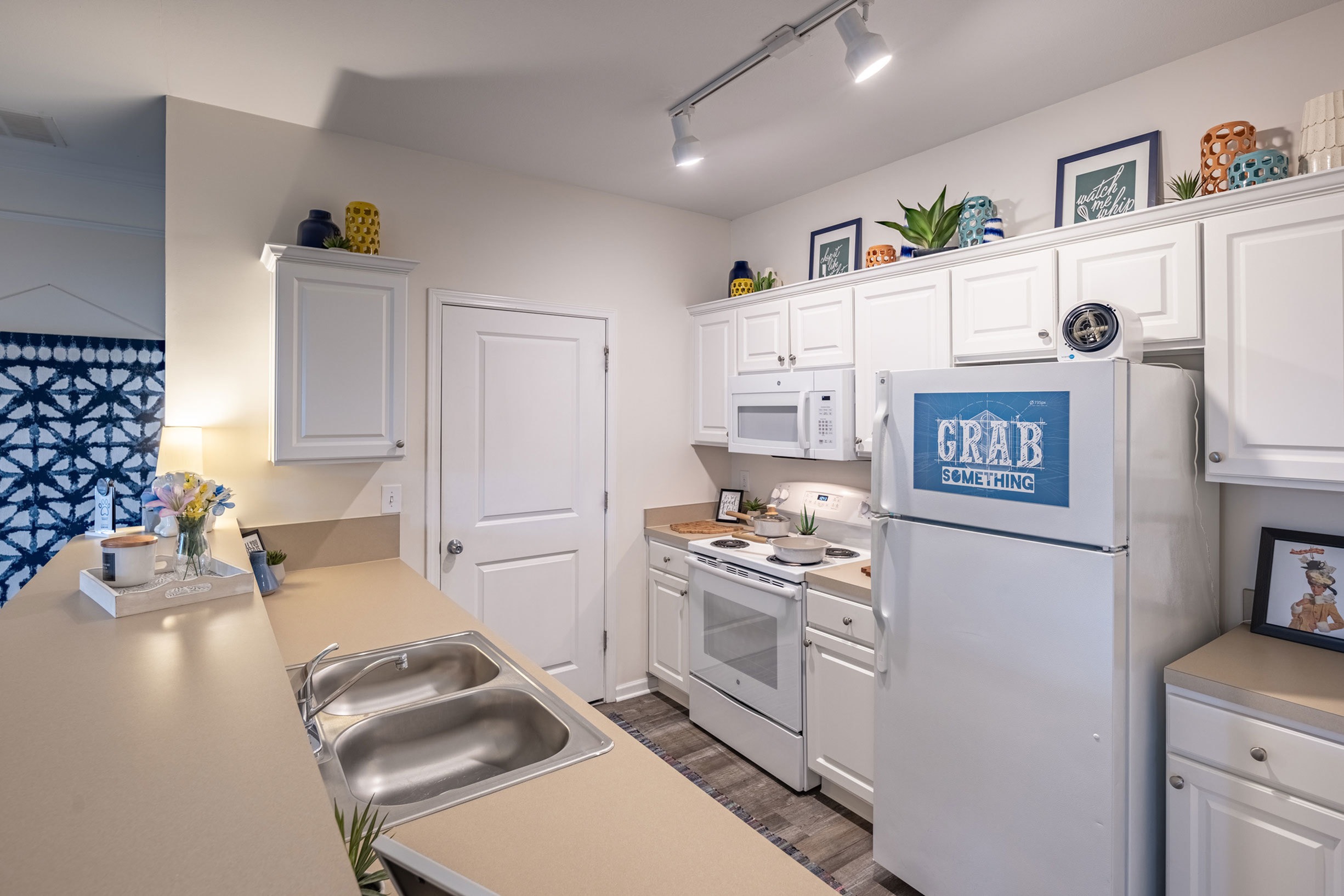 Model apartment kitchen with white appliances, white cabinets, and light counter tops.