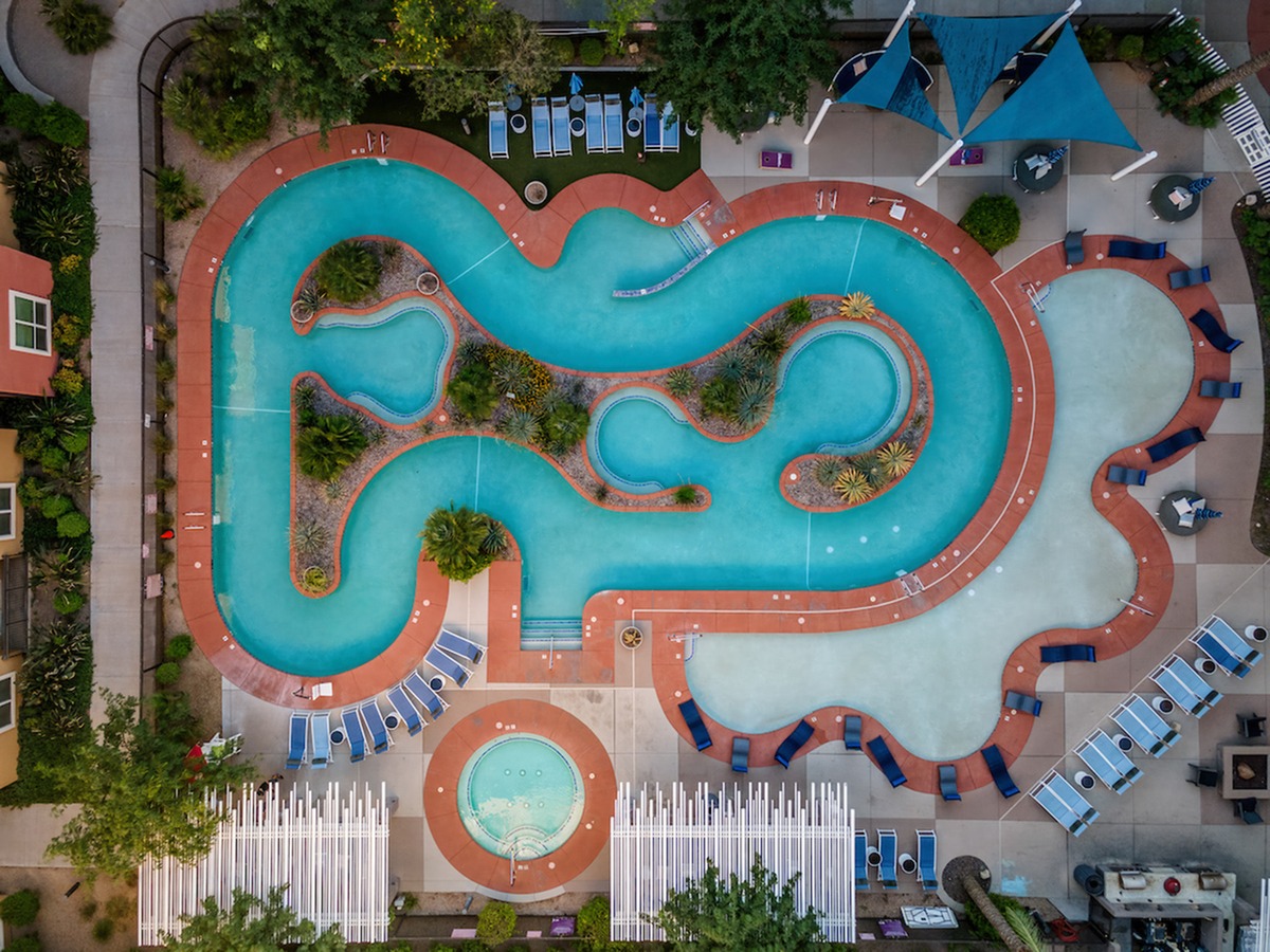 Birds eye view of the lazy river, hot tub, and tanning shelf with sun loungers and umbrellas