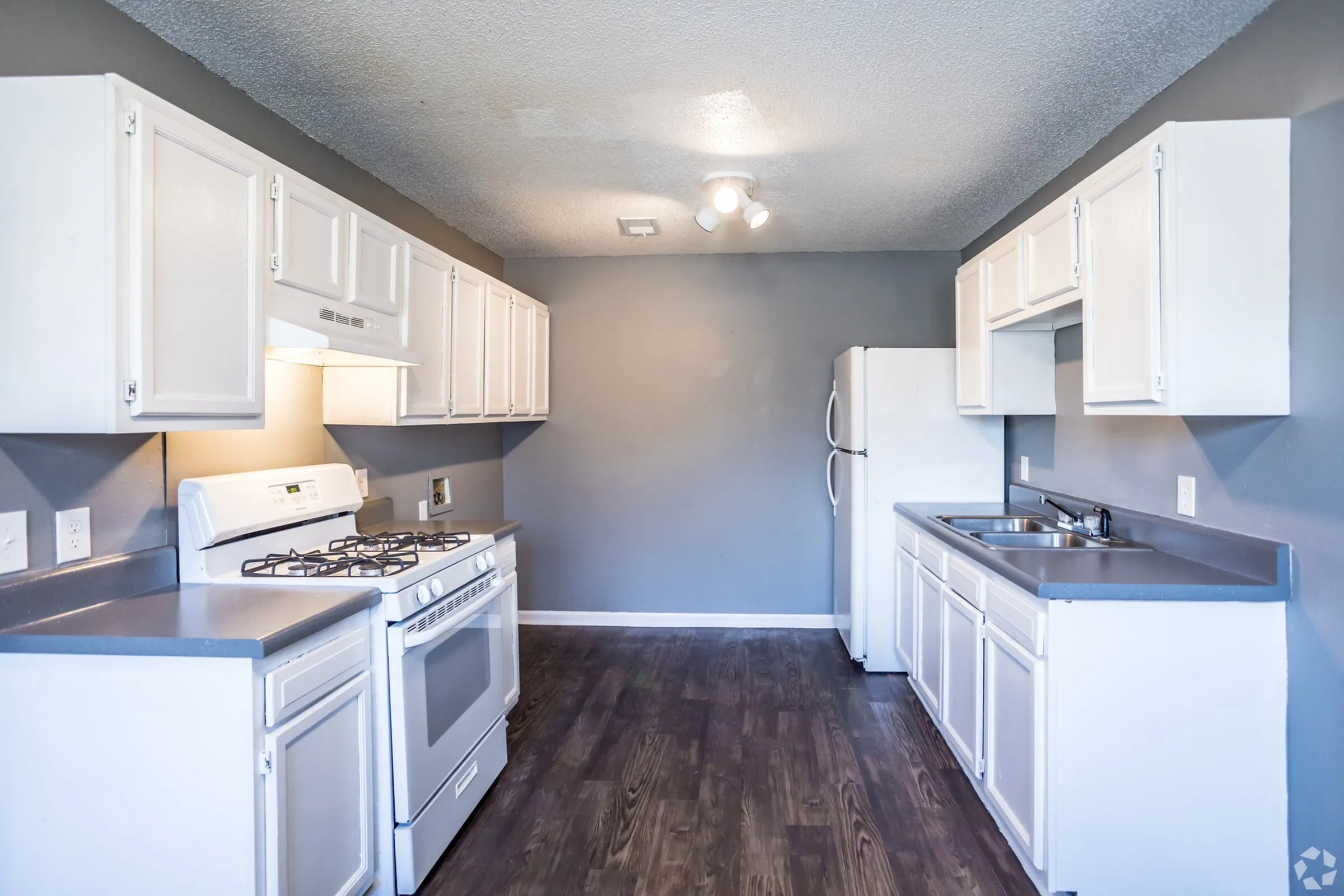 Galley kitchen with white cabinets and wood-style floors at Jackson Heights Residential in West Memphis, AR