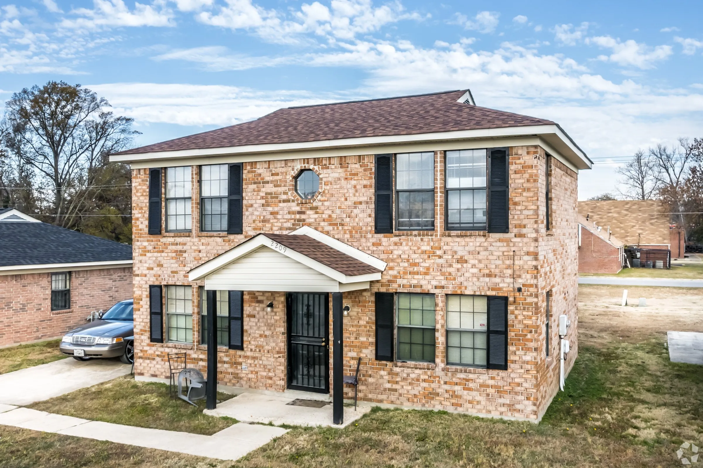 Two-story brick townhouse with black shutters at Jackson Heights Residential in West Memphis, AR