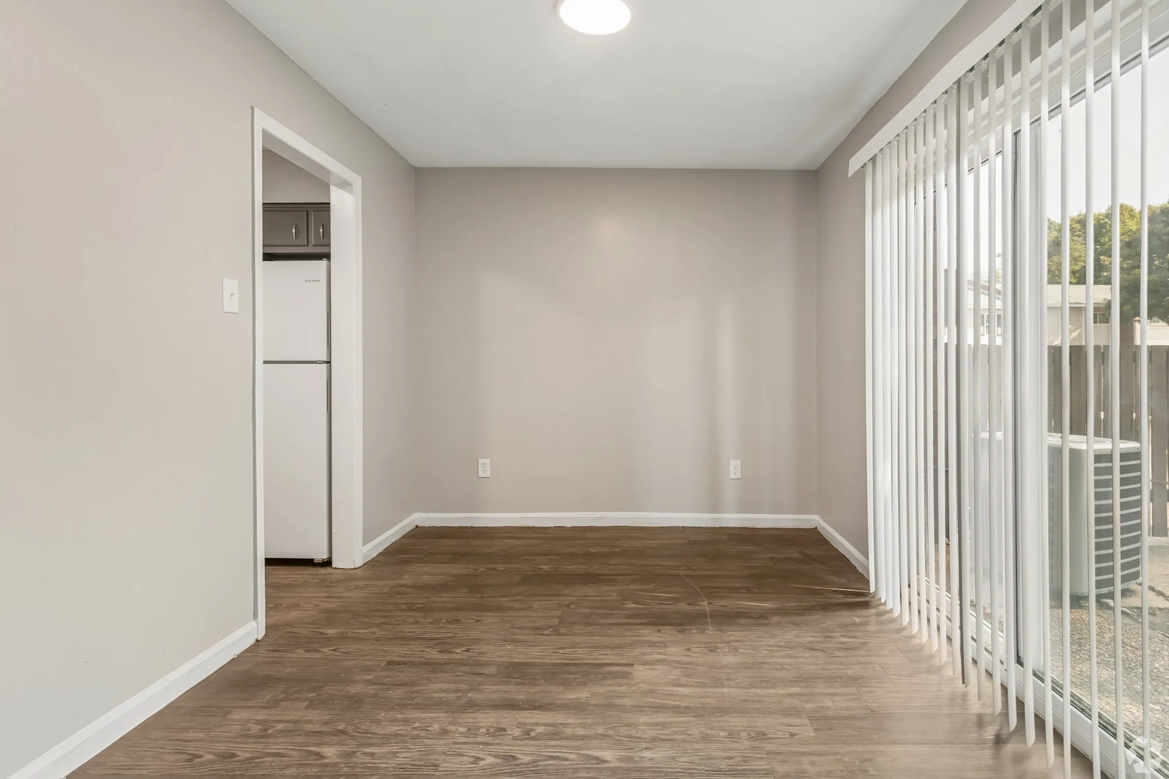 Open dining area with wood-style floors and a patio door at Shadowbrook Townhomes in Memphis, TN