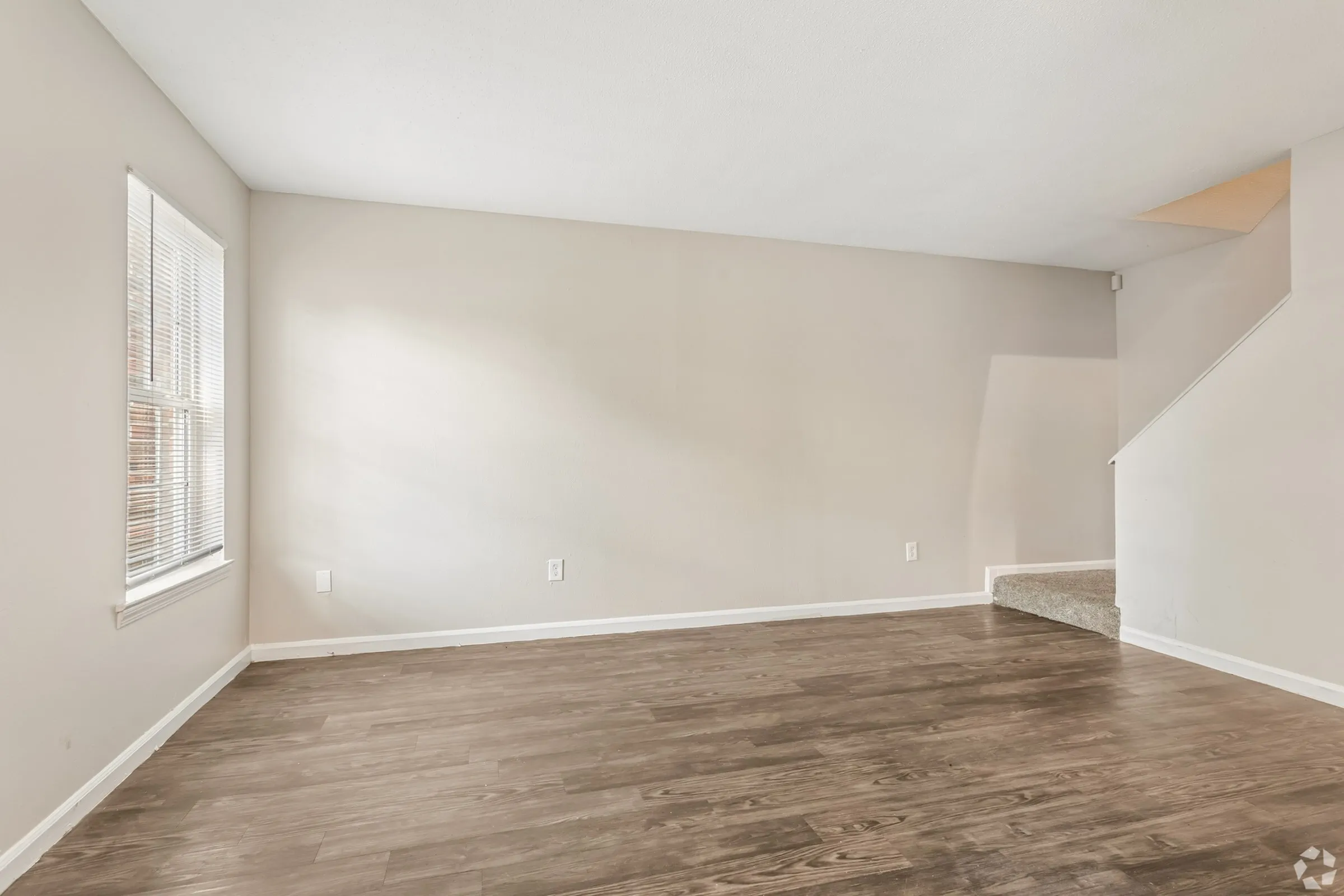 Bright living room with staircase and wood-style flooring at Shadowbrook Townhomes in Memphis, TN