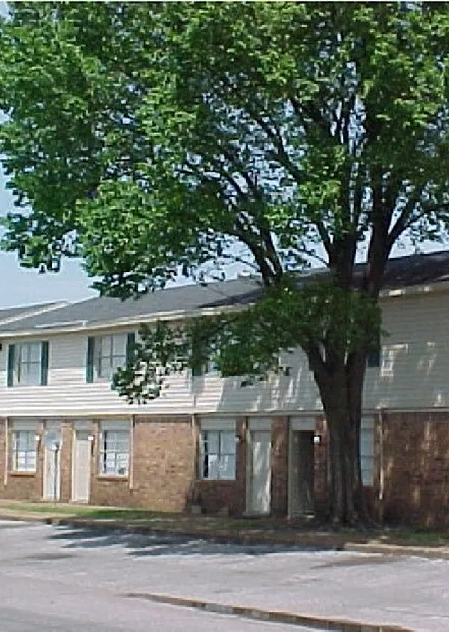 Townhome building with a large shade tree at Bent Creek Apartments in West Memphis, AR