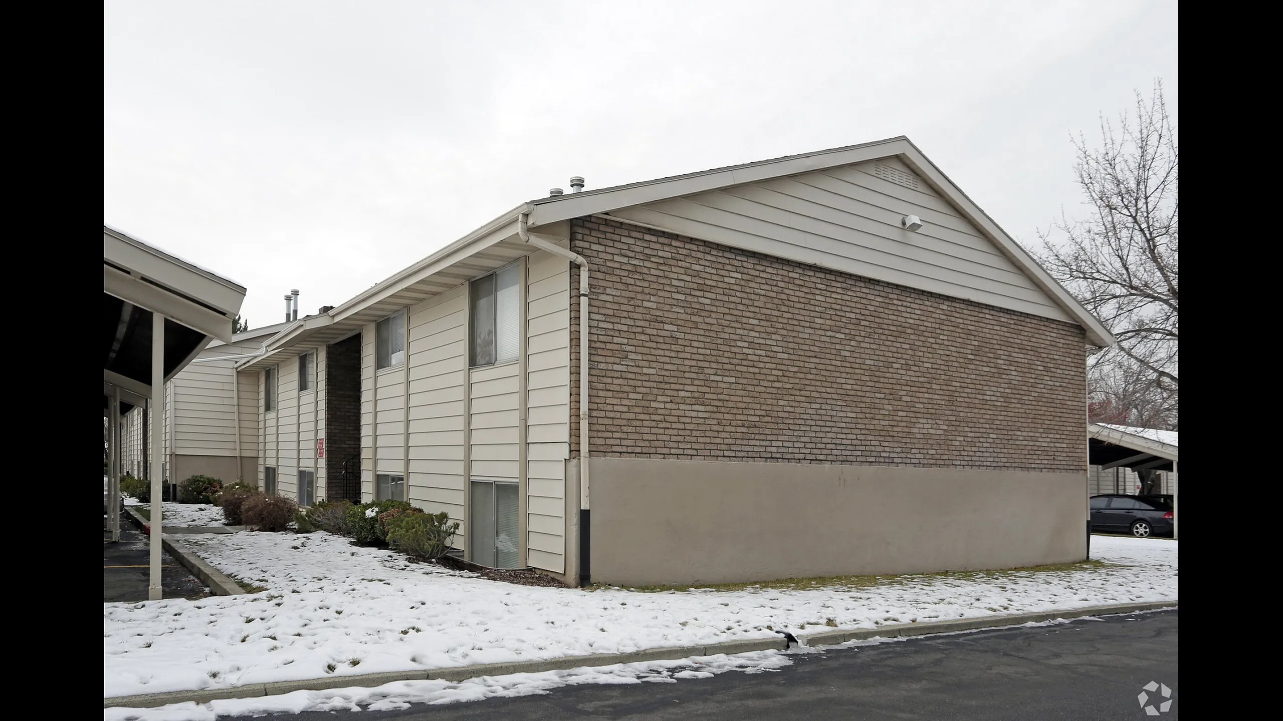 Apartment building with brick and siding after a light snow at Braewood in Murray, UT
