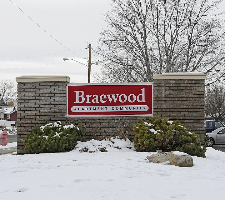 Red Braewood sign on a brick monument in the snow at Braewood in Murray, UT